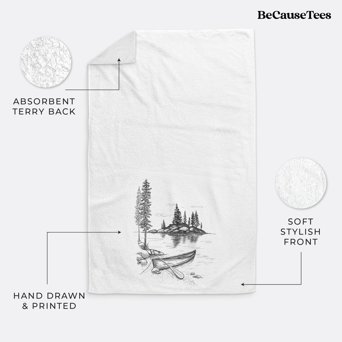 White hand towel printed with a black ink illustration of a canoe resting on the shore of a lake with pine trees on a small island.