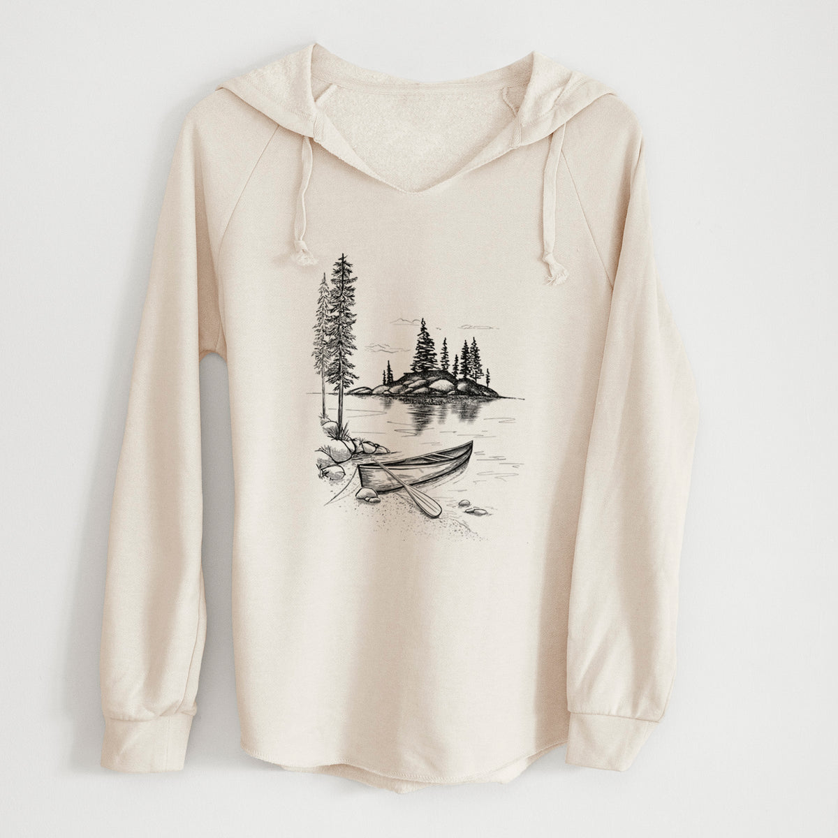 Bone cream women's Cali Wave hooded sweatshirt laid flat, printed with a black ink illustration of a canoe resting on the shore of a lake with pine trees on a small island.