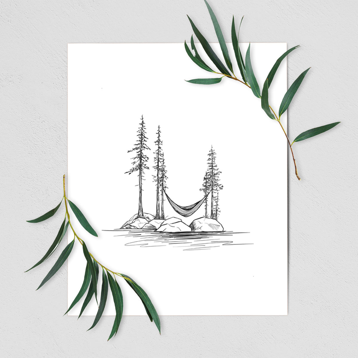 Art print of a black ink illustration of a hammock strung between pine trees on a small lakeside island, shown with eucalyptus leaves.