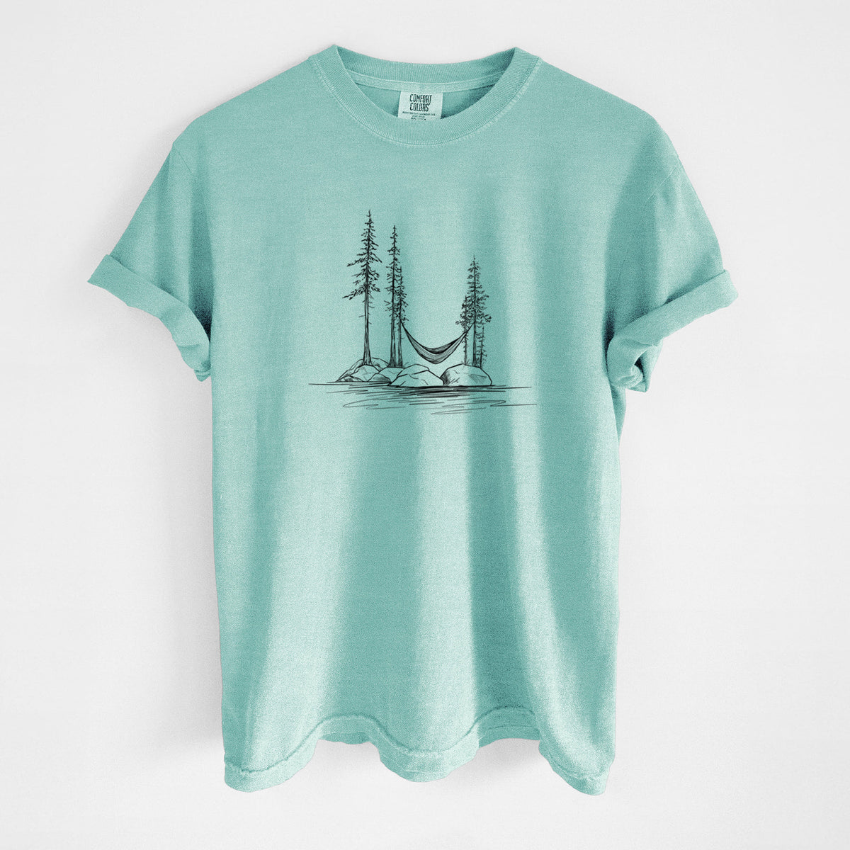 Chalky mint Comfort Colors t-shirt laid flat, printed with a black ink illustration of a hammock strung between pine trees on a small lakeside island.