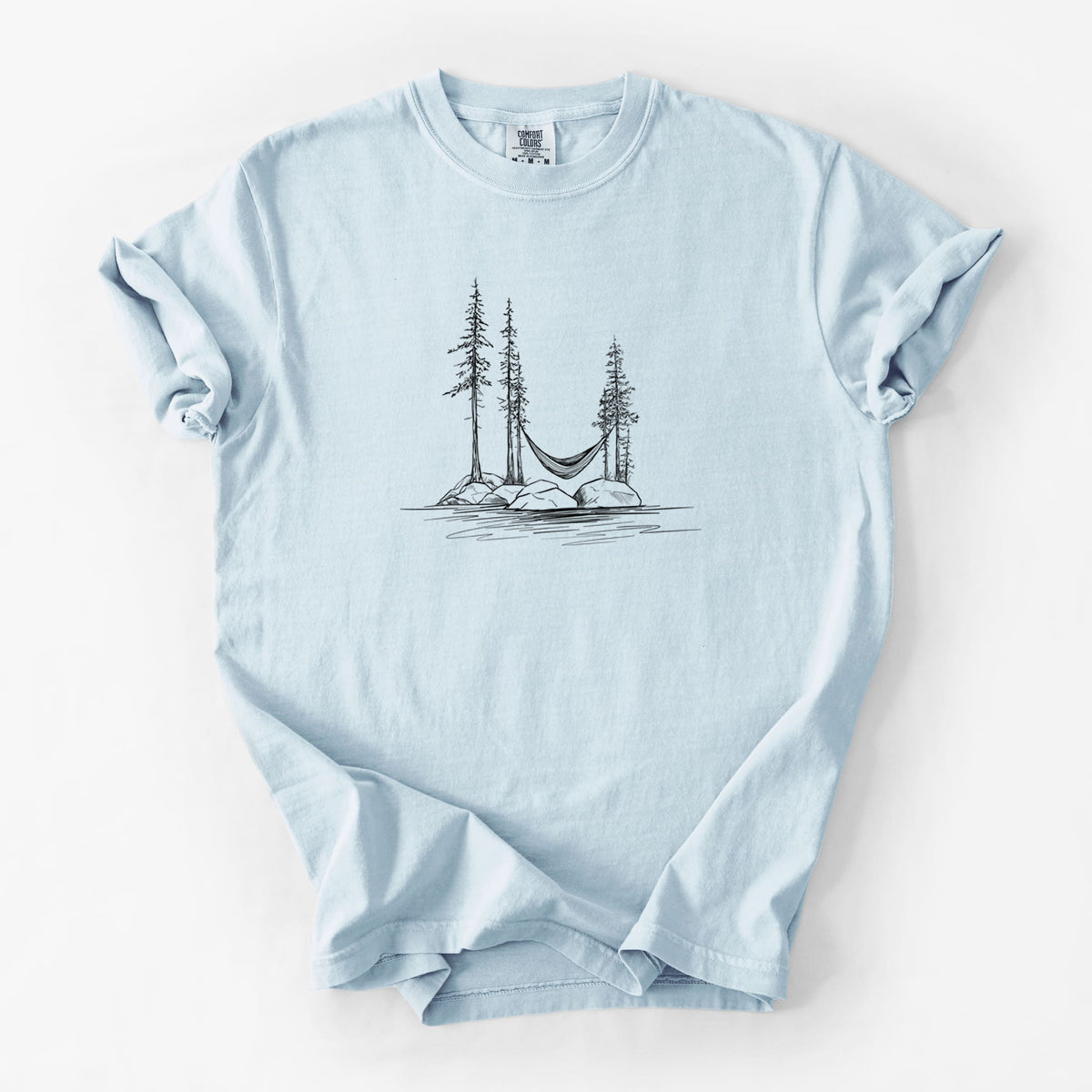 Chambray blue Comfort Colors t-shirt laid flat, printed with a black ink illustration of a hammock strung between pine trees on a small lakeside island.