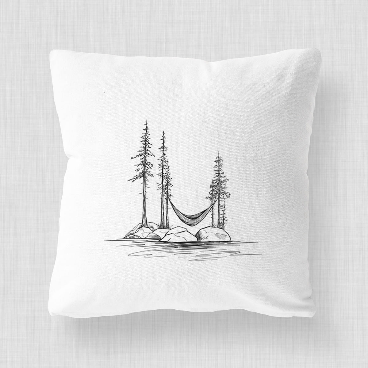 White pillow cover printed with a black ink illustration of a hammock strung between pine trees on a small lakeside island.