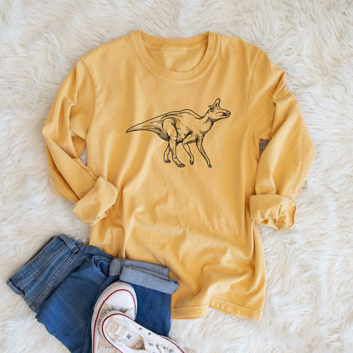 Golden wheat yellow Comfort Colors long sleeve shirt printed with a black ink illustration of a crested Lambeosaurus walking, shown in a lifestyle photo.