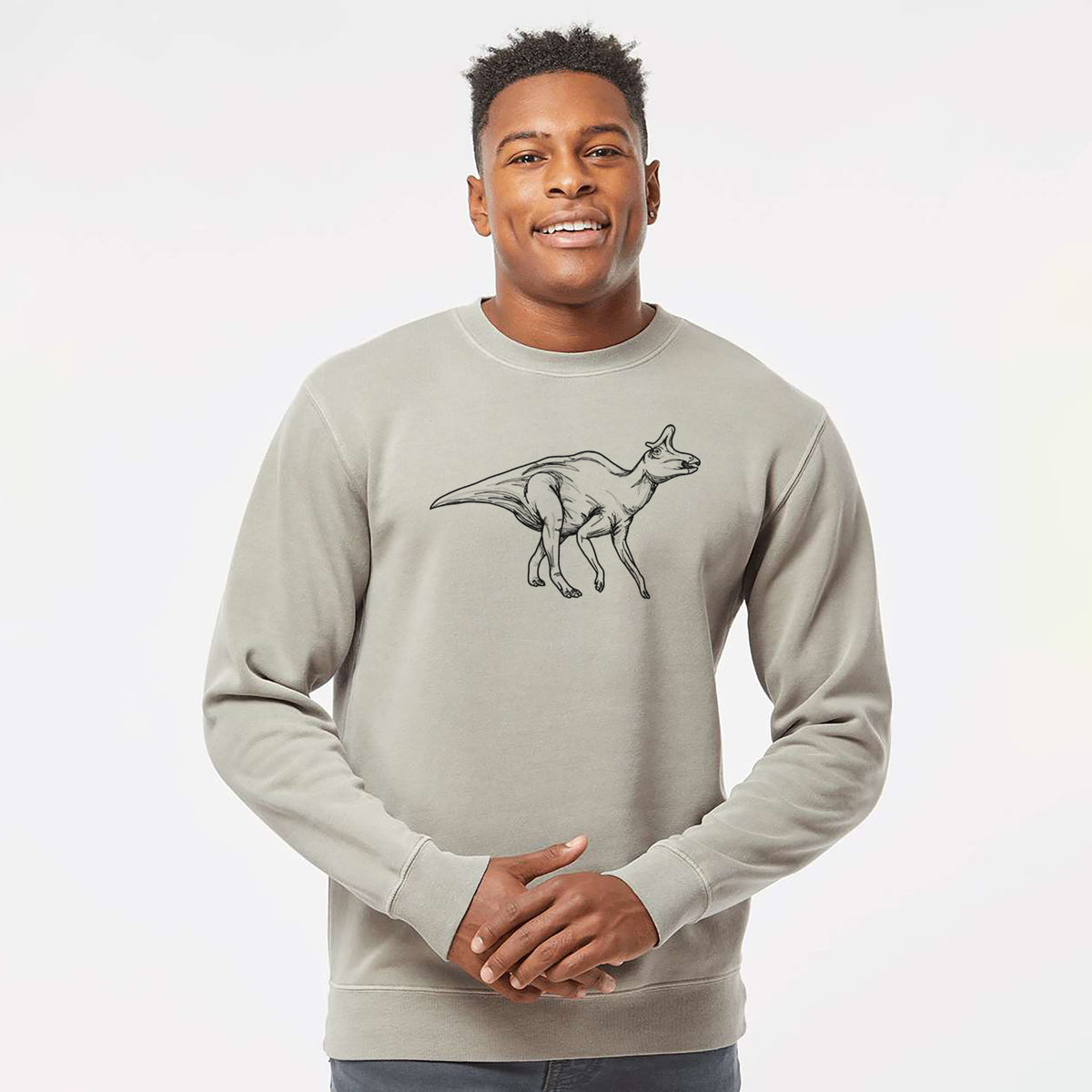 Model wearing a cement grey pigment dyed crewneck sweatshirt printed with a black ink illustration of a crested Lambeosaurus walking.