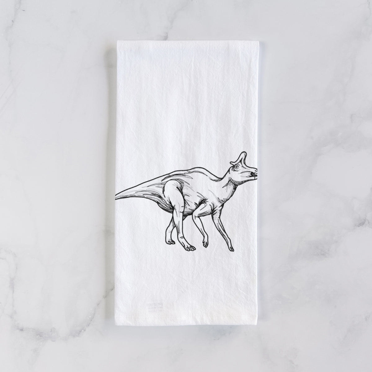 White cotton tea towel laid flat on marble, printed with a black ink illustration of a crested Lambeosaurus walking.