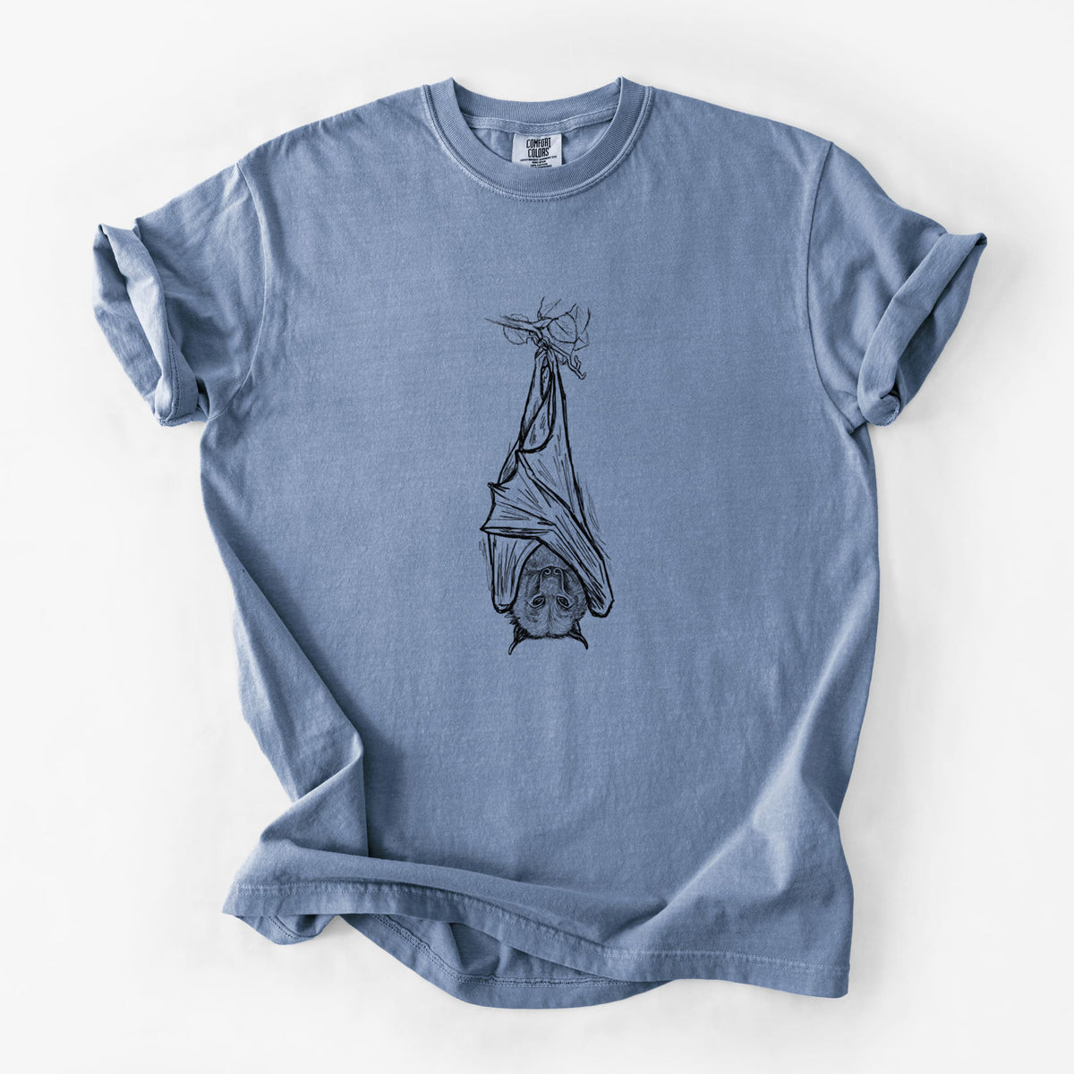 Blue jean Comfort Colors t-shirt laid flat, printed with a black ink illustration of a large flying fox bat hanging upside down with its wings wrapped around it.