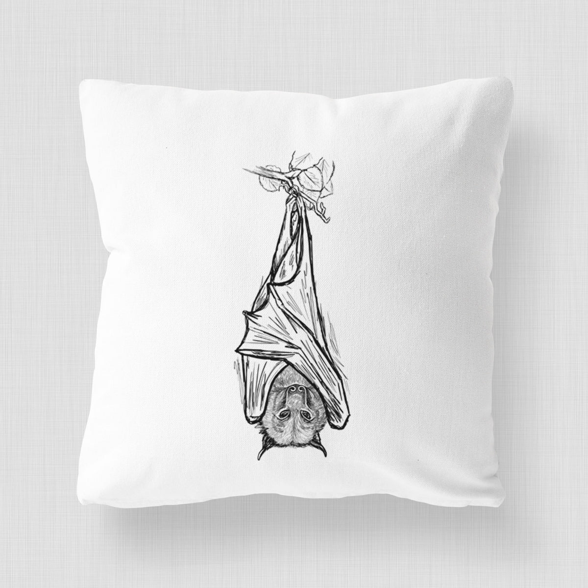 White pillow cover printed with a black ink illustration of a large flying fox bat hanging upside down with its wings wrapped around it.