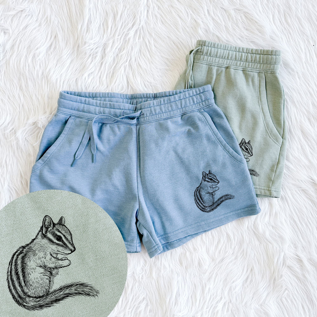 Two pairs of Cali Wave shorts in different colors printed with a detailed black ink illustration of a least chipmunk sitting and holding food in its paws, with a close-up of the print.