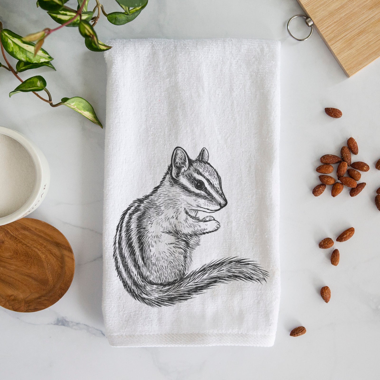 White hand towel printed with a detailed black ink illustration of a least chipmunk sitting and holding food in its paws.