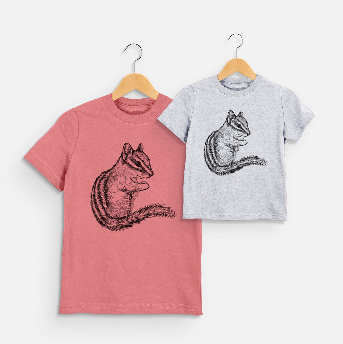 Two youth t-shirts in different colors on hangers, printed with a detailed black ink illustration of a least chipmunk sitting and holding food in its paws.
