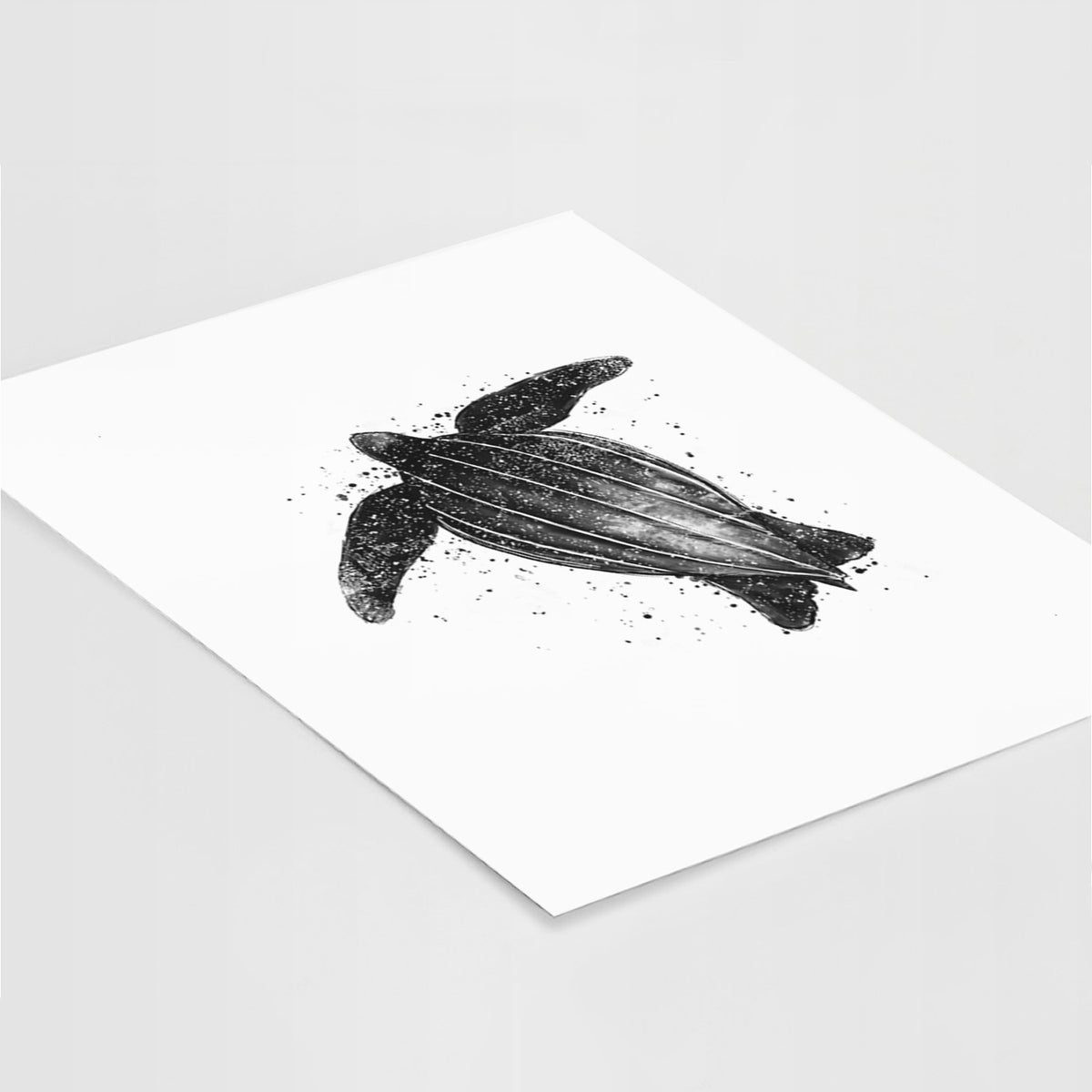Art print of a black ink illustration of a leatherback sea turtle swimming, with ink splatters, lying at an angle on a white surface.