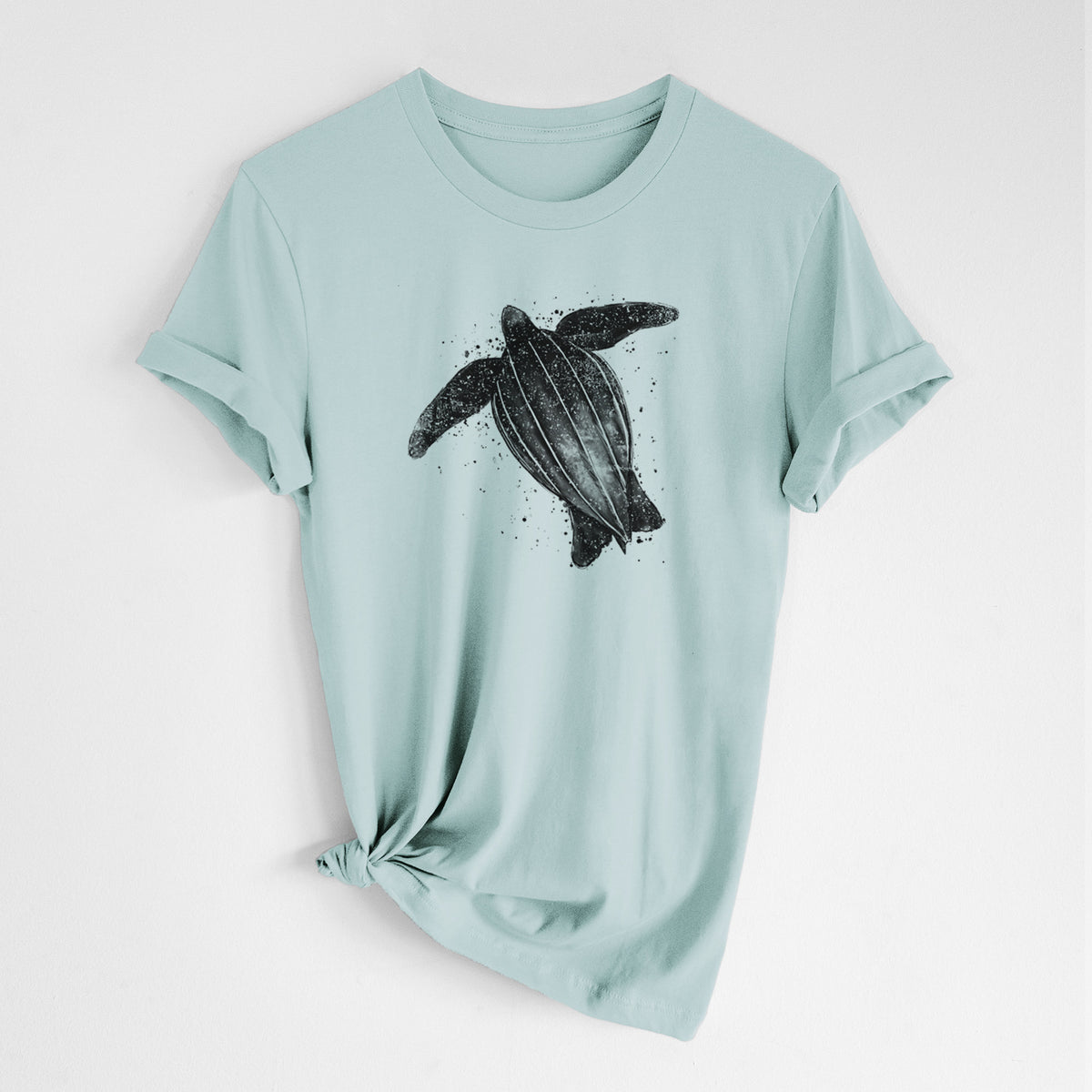 Dusty blue lightweight cotton t-shirt laid flat with the sleeves rolled, printed with a black ink illustration of a leatherback sea turtle swimming, with ink splatters.