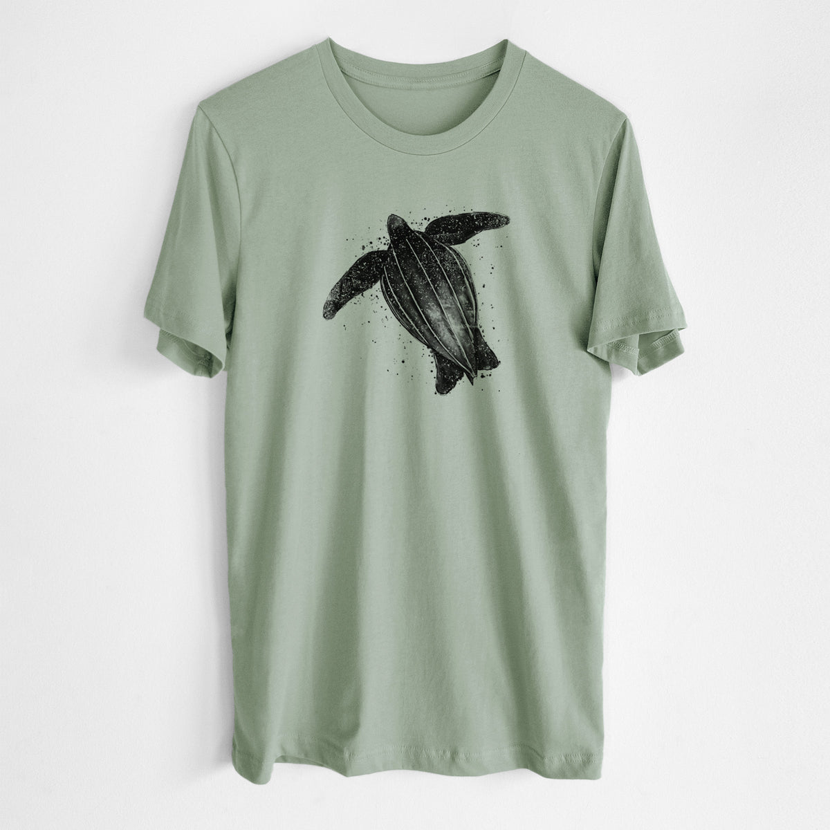 Sage green lightweight cotton t-shirt laid flat, printed with a black ink illustration of a leatherback sea turtle swimming, with ink splatters.