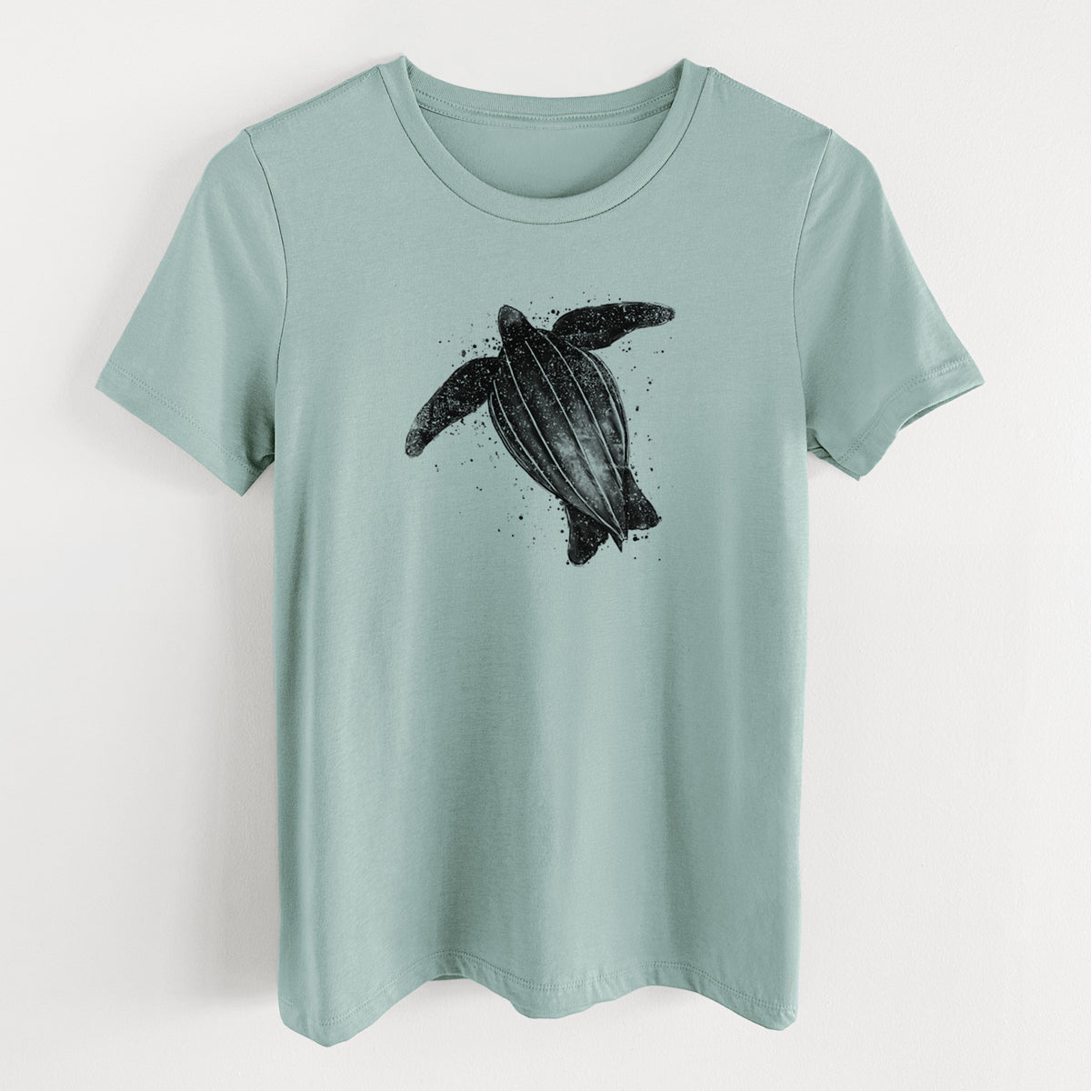 Dusty blue women's relaxed fit cotton t-shirt laid flat, printed with a black ink illustration of a leatherback sea turtle swimming, with ink splatters.