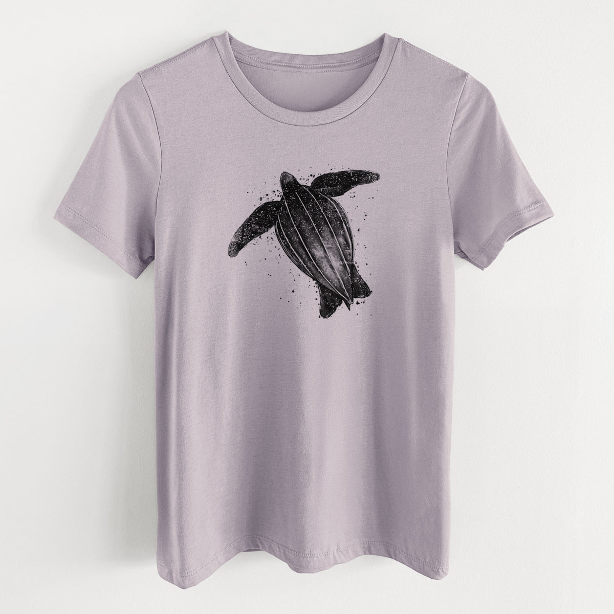 Light violet women's relaxed fit cotton t-shirt laid flat, printed with a black ink illustration of a leatherback sea turtle swimming, with ink splatters.