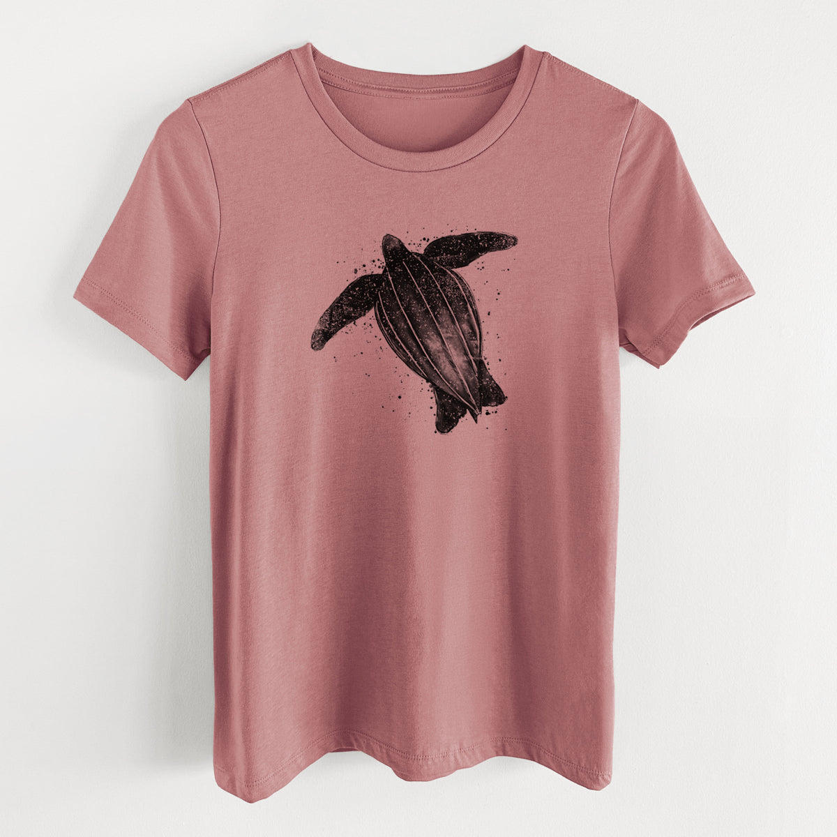 Mauve pink women's relaxed fit cotton t-shirt laid flat, printed with a black ink illustration of a leatherback sea turtle swimming, with ink splatters.