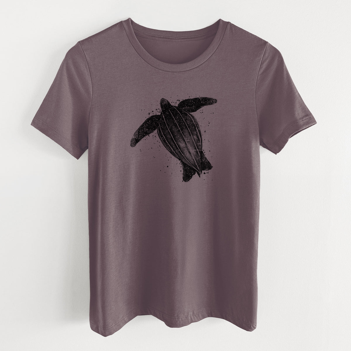 Purple storm women's relaxed fit cotton t-shirt laid flat, printed with a black ink illustration of a leatherback sea turtle swimming, with ink splatters.