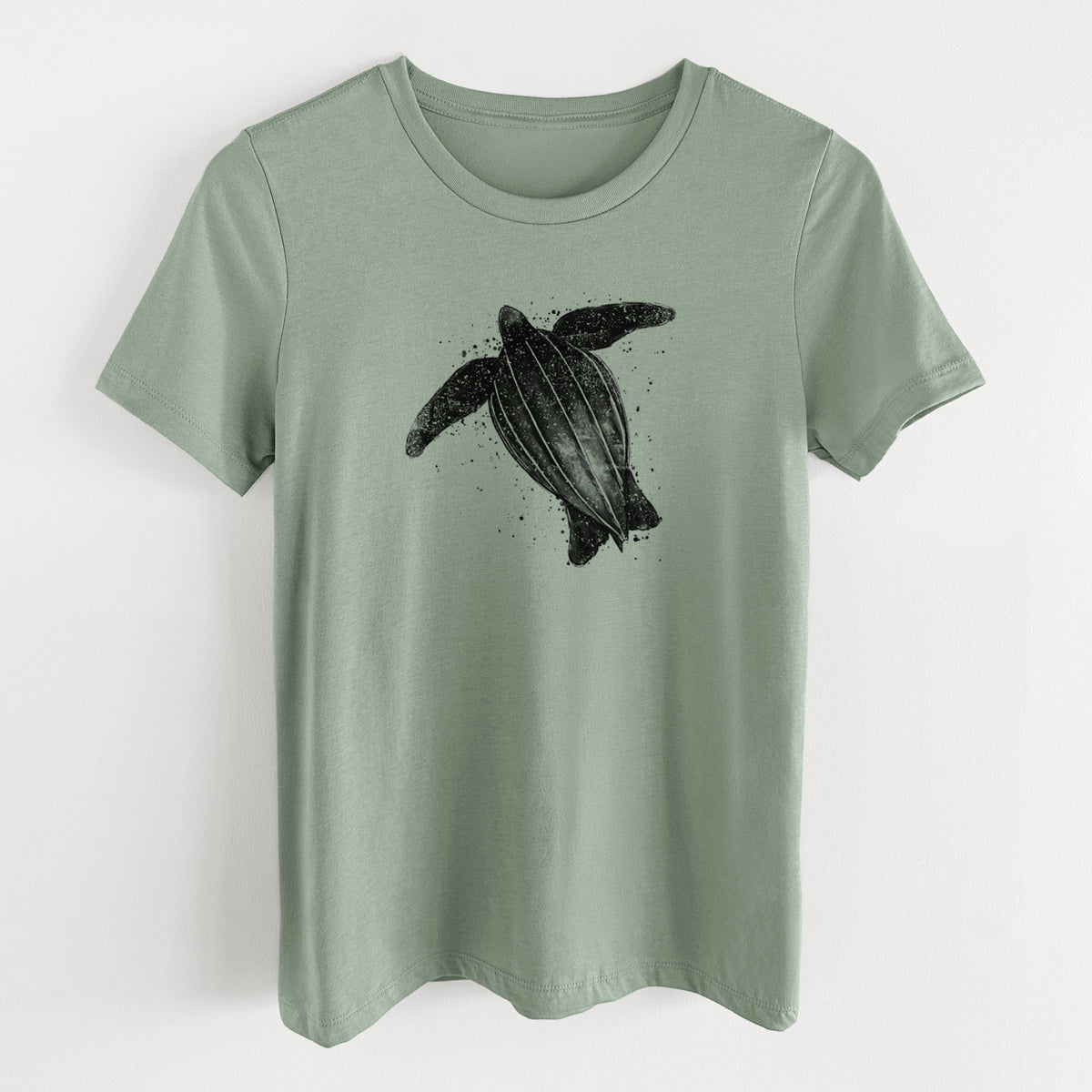 Sage green women's relaxed fit cotton t-shirt laid flat, printed with a black ink illustration of a leatherback sea turtle swimming, with ink splatters.