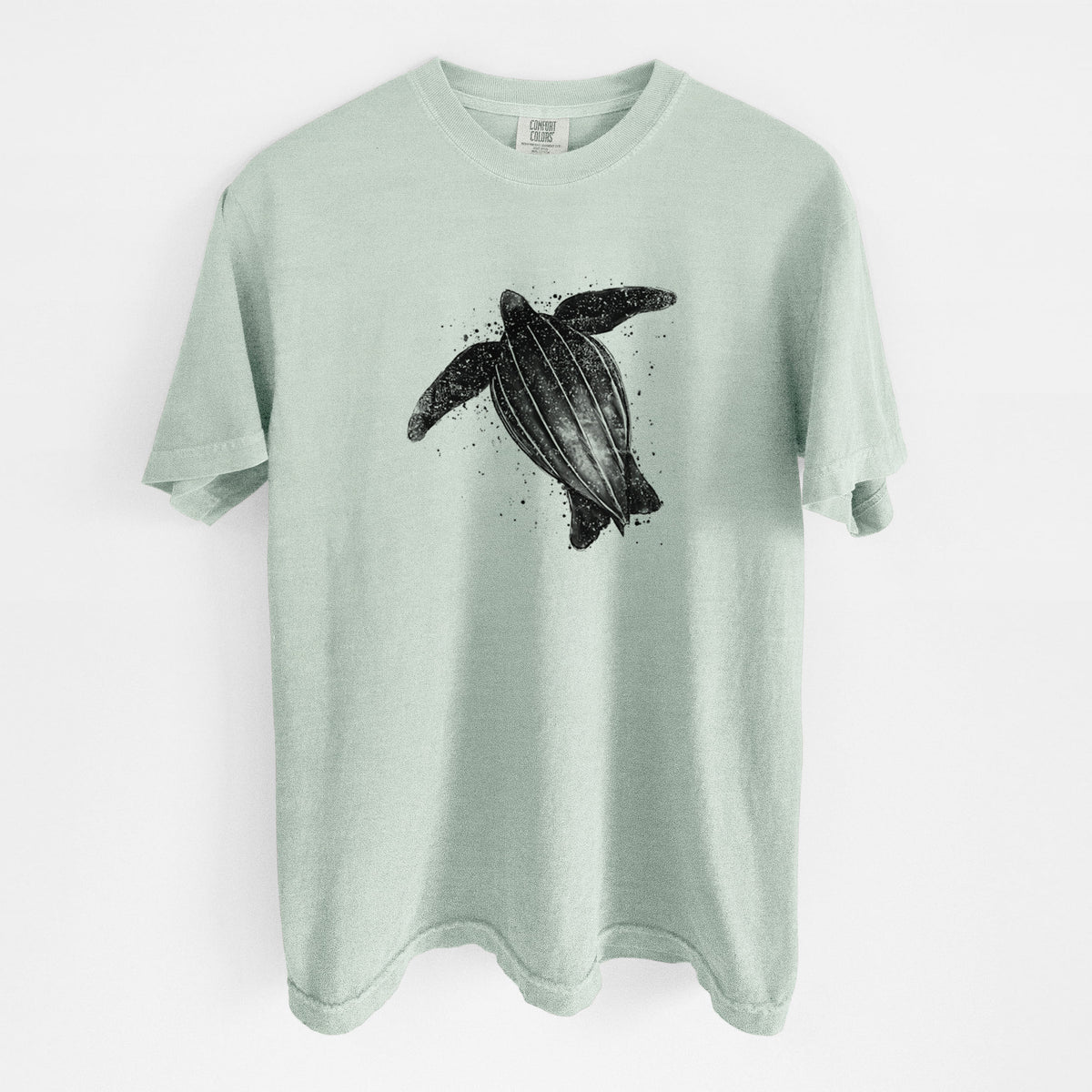 Bay green Comfort Colors t-shirt laid flat, printed with a black ink illustration of a leatherback sea turtle swimming, with ink splatters.