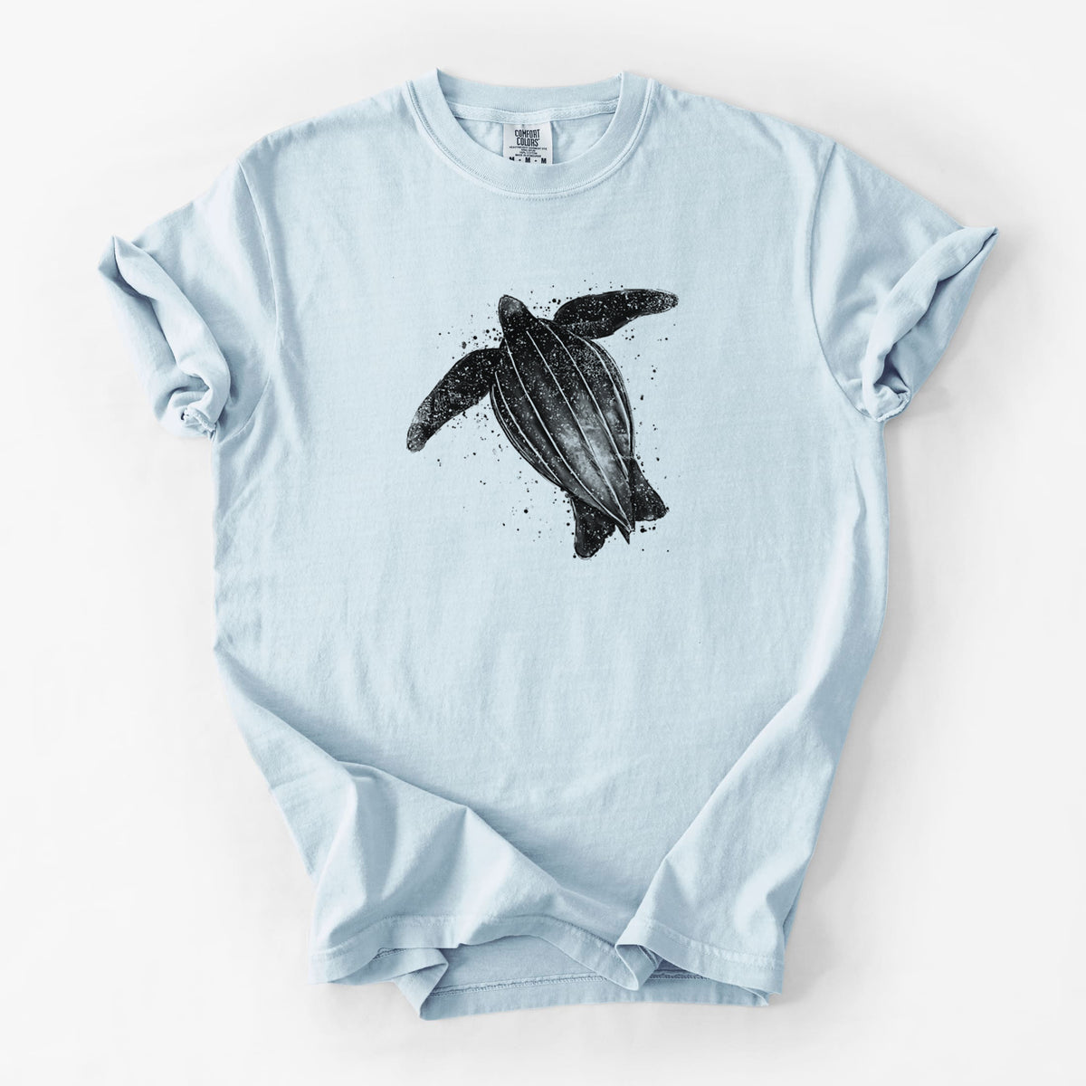 Chambray blue Comfort Colors t-shirt laid flat, printed with a black ink illustration of a leatherback sea turtle swimming, with ink splatters.