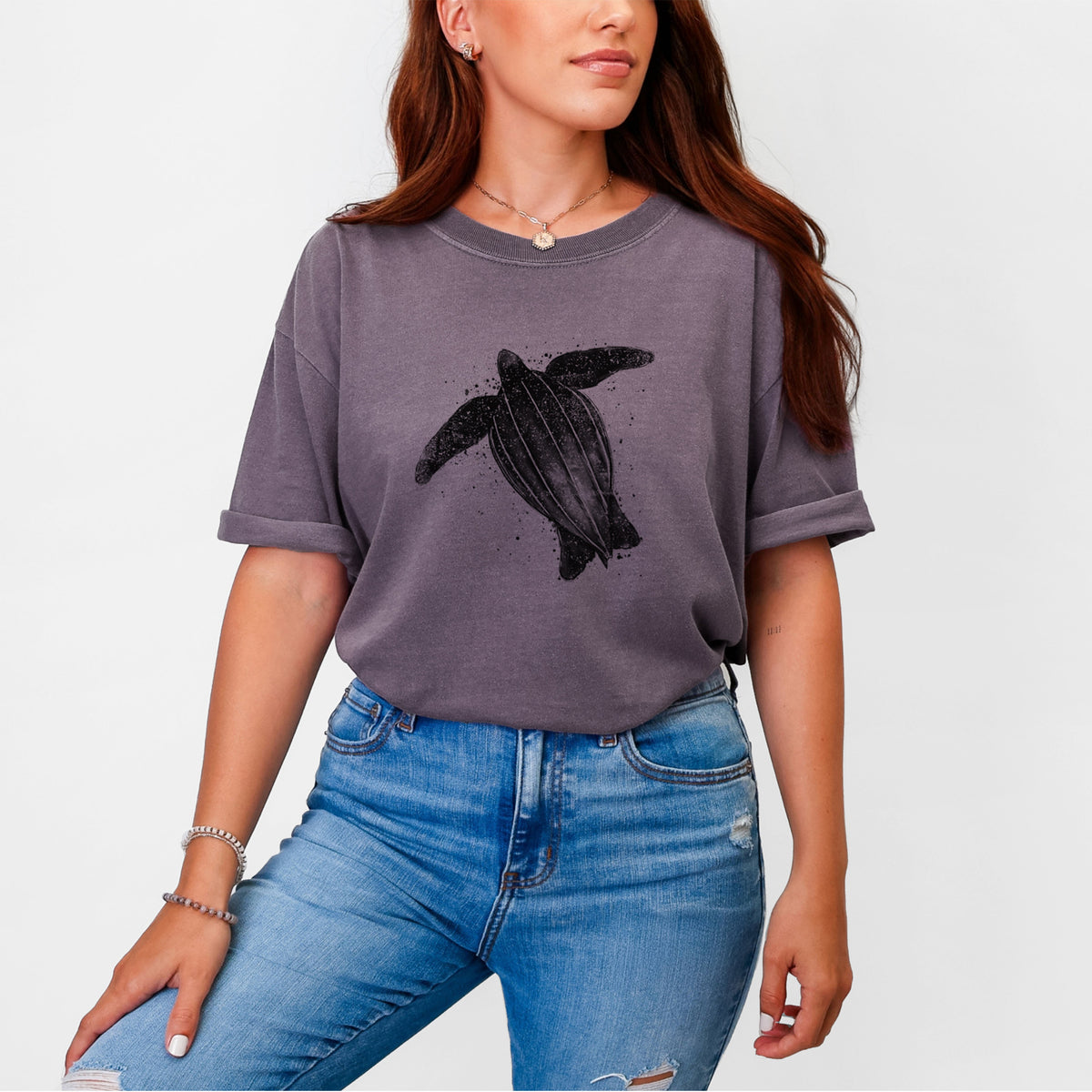 Woman wearing a Comfort Colors t-shirt printed with a black ink illustration of a leatherback sea turtle swimming, with ink splatters.