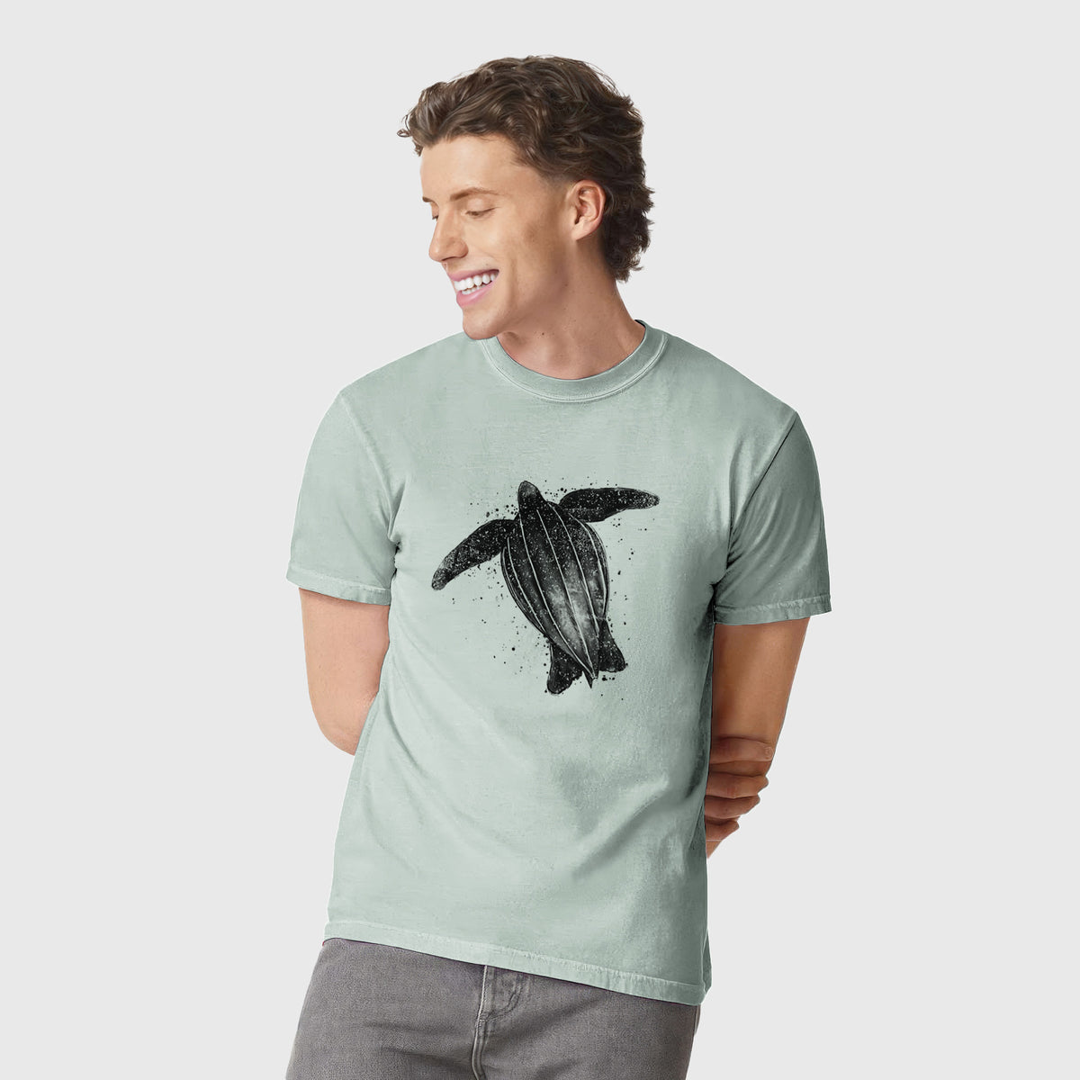 Man wearing a Comfort Colors t-shirt printed with a black ink illustration of a leatherback sea turtle swimming, with ink splatters.