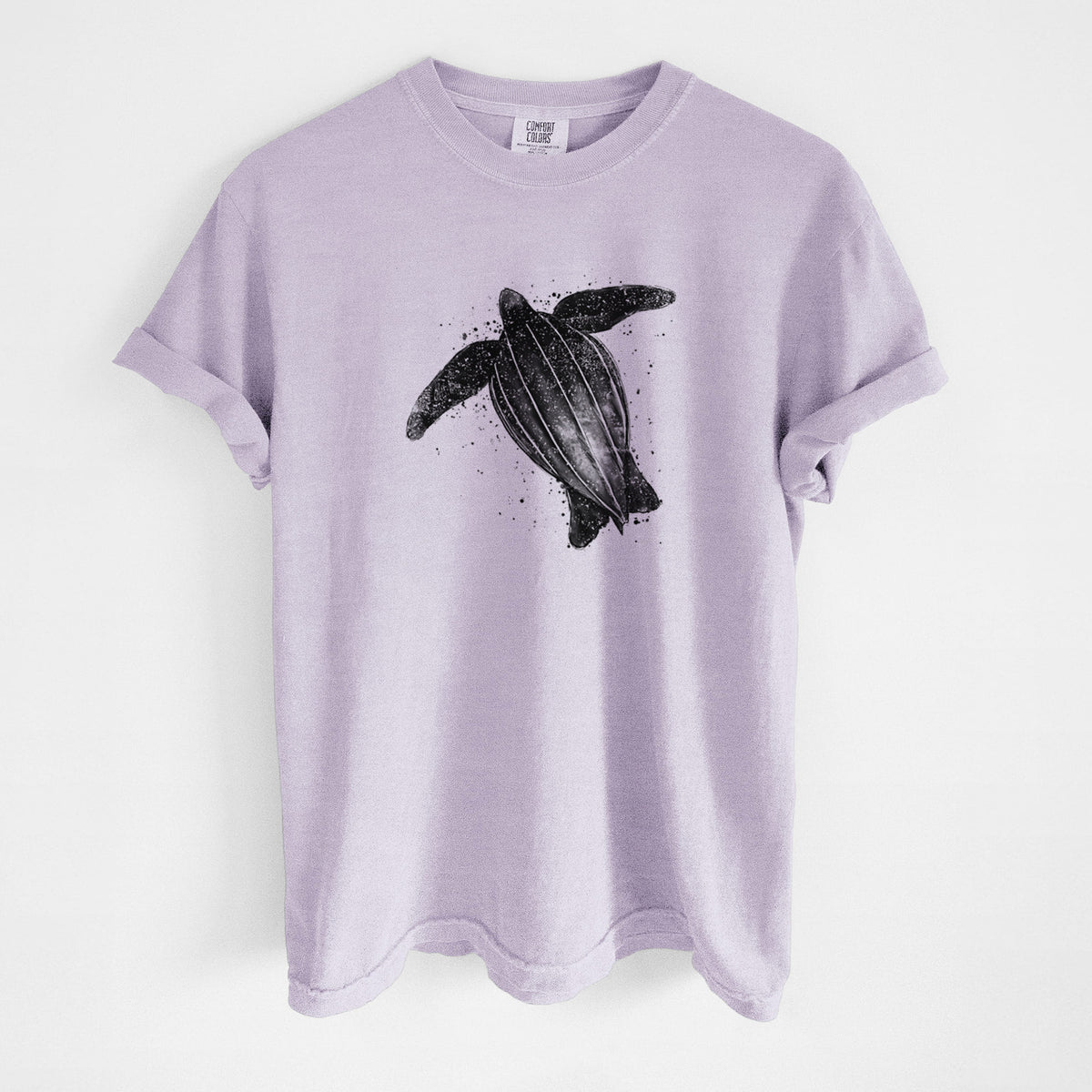Orchid purple Comfort Colors t-shirt laid flat, printed with a black ink illustration of a leatherback sea turtle swimming, with ink splatters.