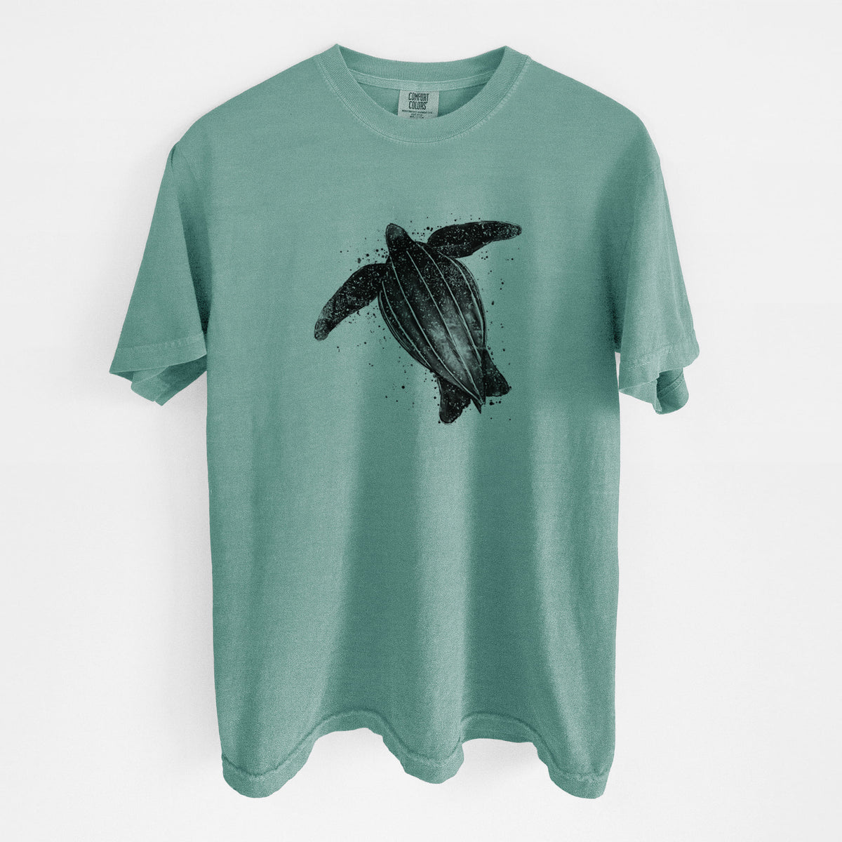 Reef green Comfort Colors t-shirt laid flat, printed with a black ink illustration of a leatherback sea turtle swimming, with ink splatters.