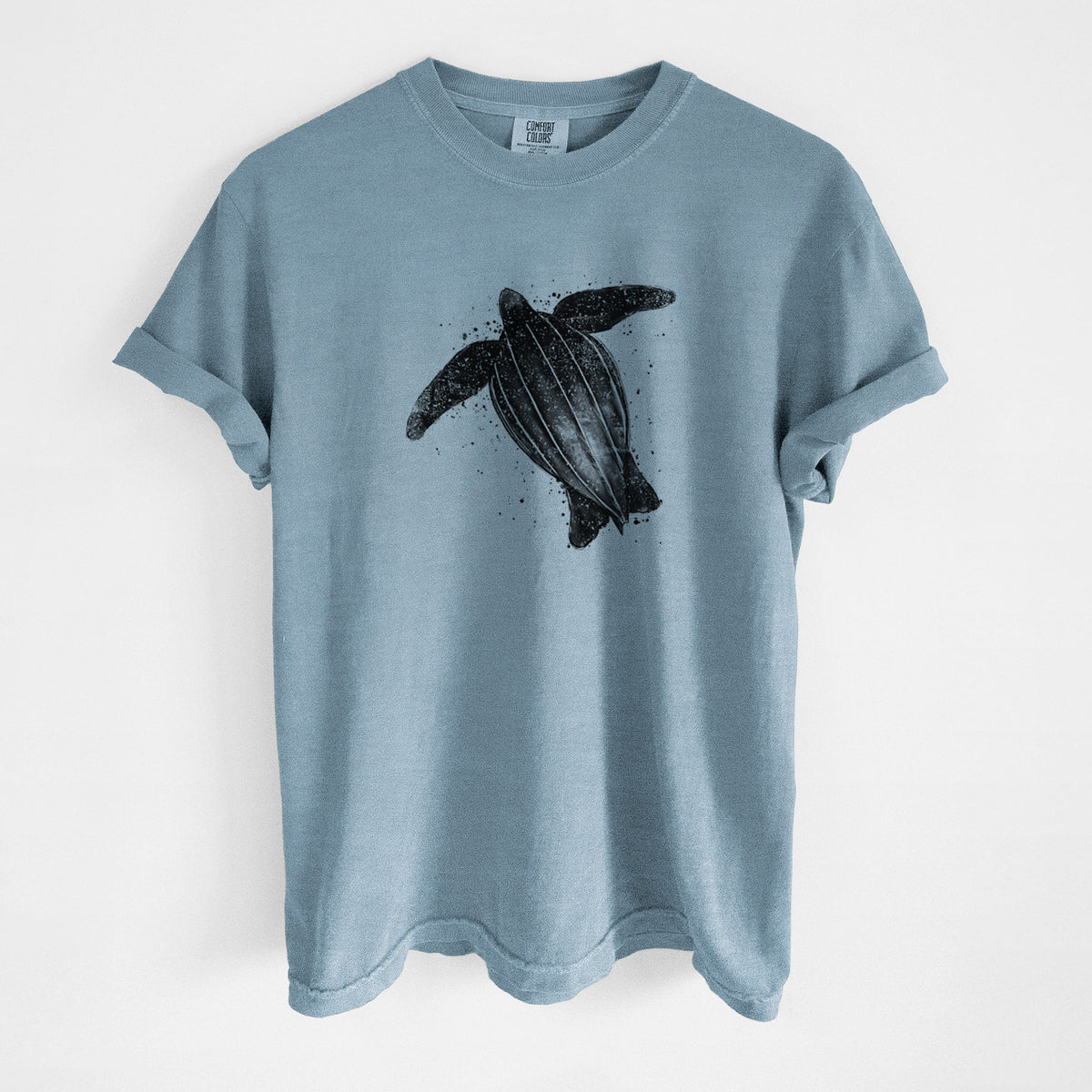 Steel blue Comfort Colors t-shirt laid flat, printed with a black ink illustration of a leatherback sea turtle swimming, with ink splatters.