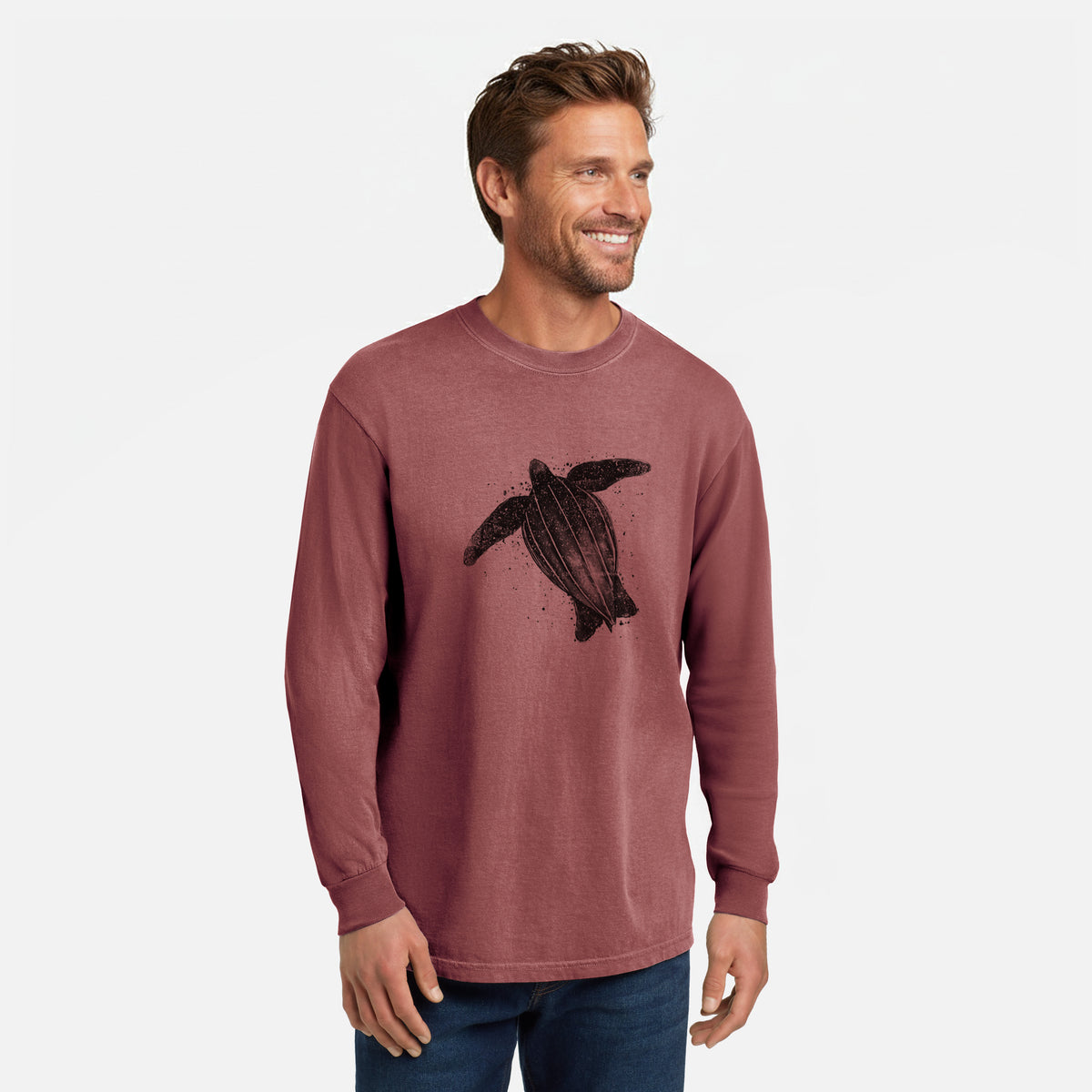 Brick red Comfort Colors long sleeve shirt printed with a black ink illustration of a leatherback sea turtle swimming, with ink splatters, shown in a lifestyle photo.
