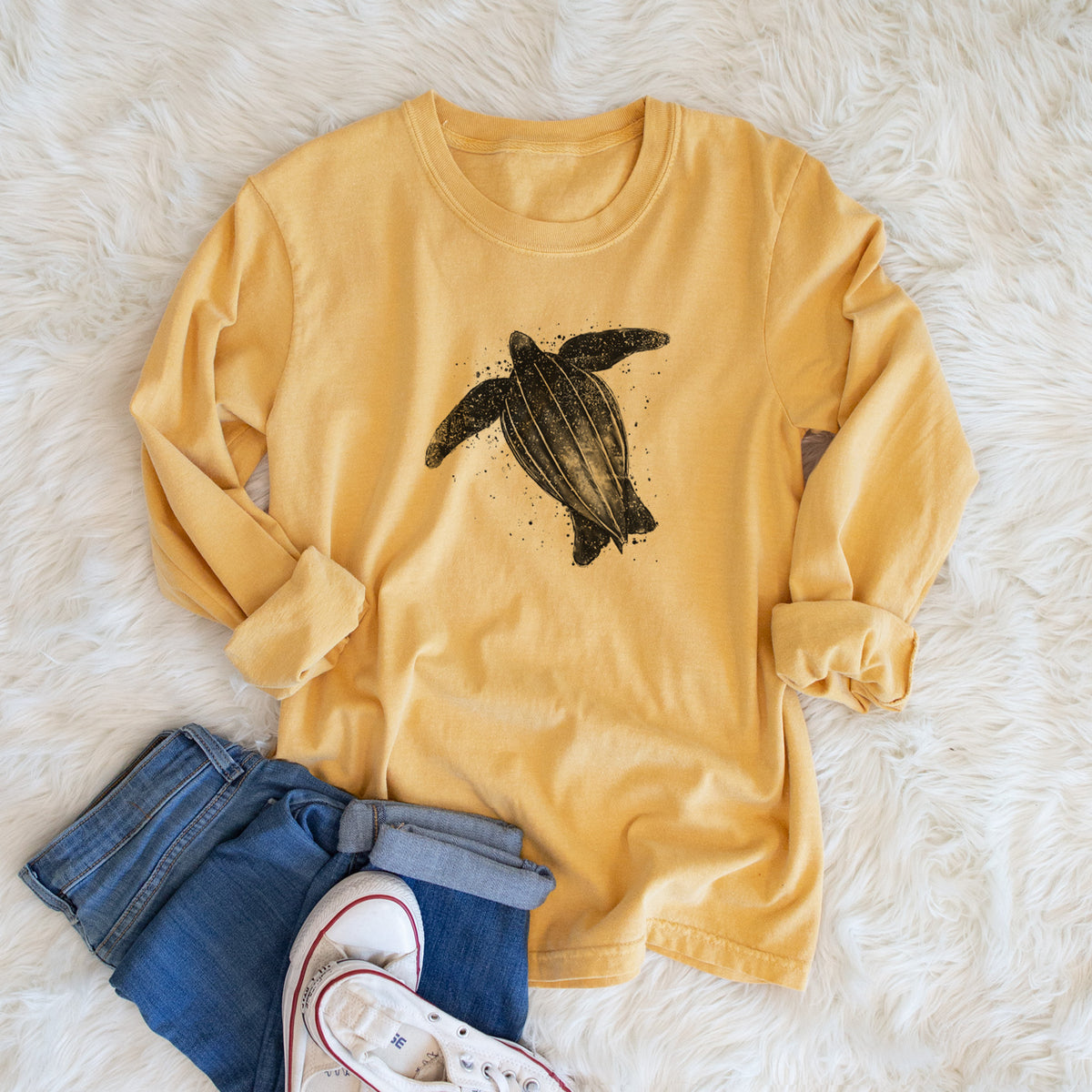 Golden wheat yellow Comfort Colors long sleeve shirt printed with a black ink illustration of a leatherback sea turtle swimming, with ink splatters, shown in a lifestyle photo.