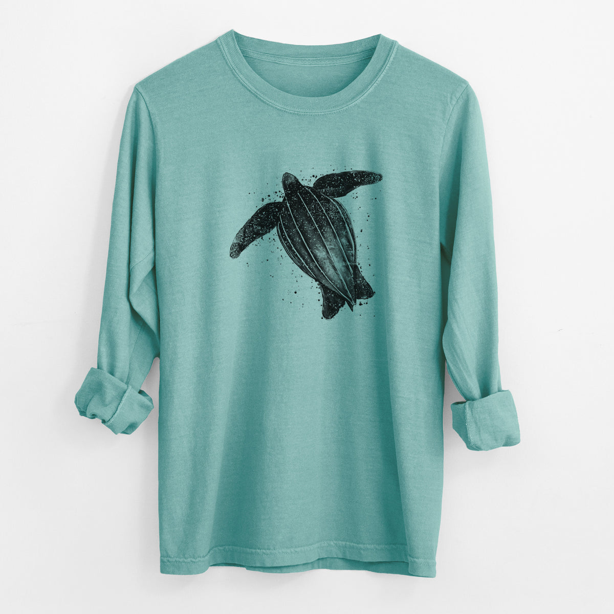 Reef green Comfort Colors long sleeve shirt laid flat with the cuffs rolled, printed with a black ink illustration of a leatherback sea turtle swimming, with ink splatters.