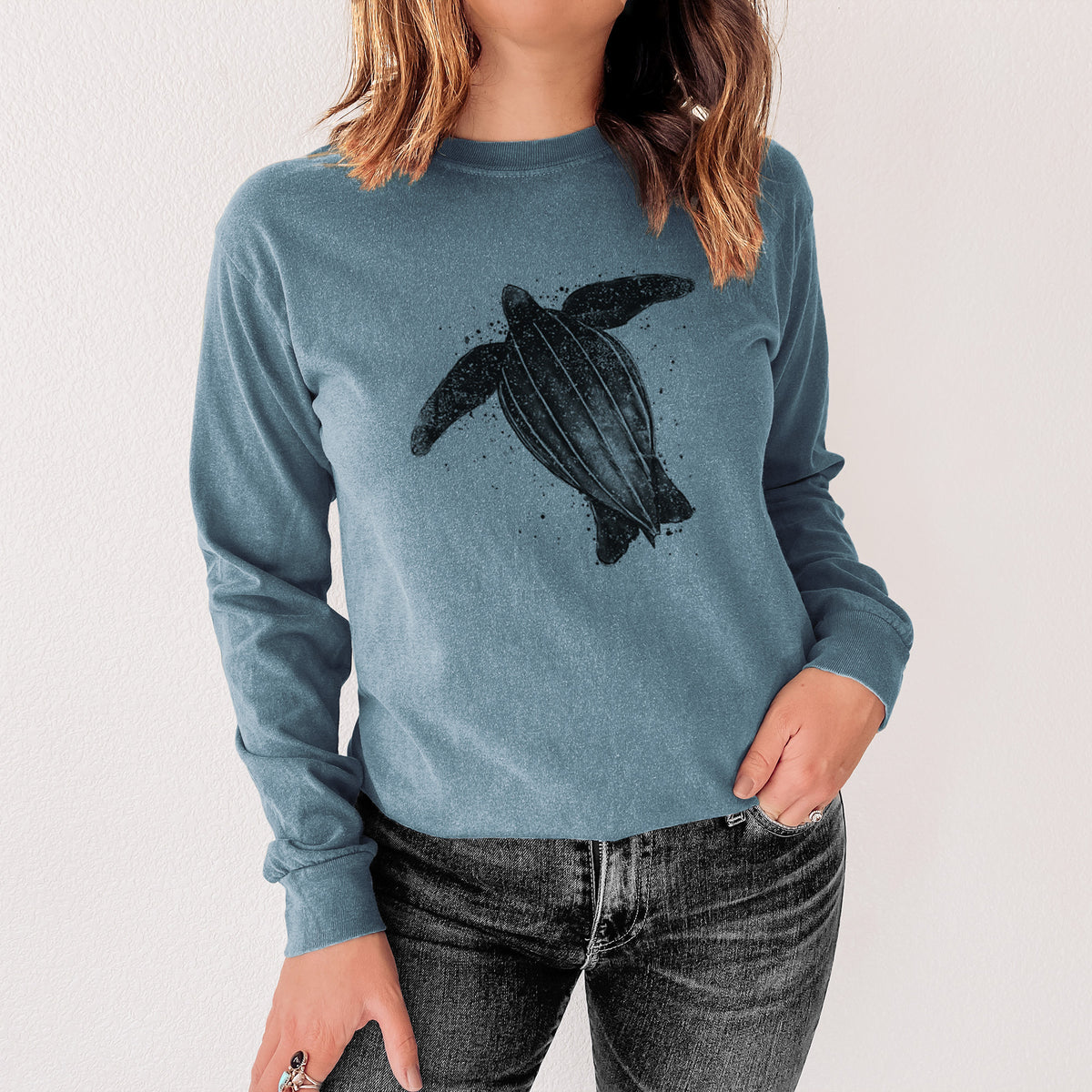 Steel blue Comfort Colors long sleeve shirt printed with a black ink illustration of a leatherback sea turtle swimming, with ink splatters, shown in a lifestyle photo.