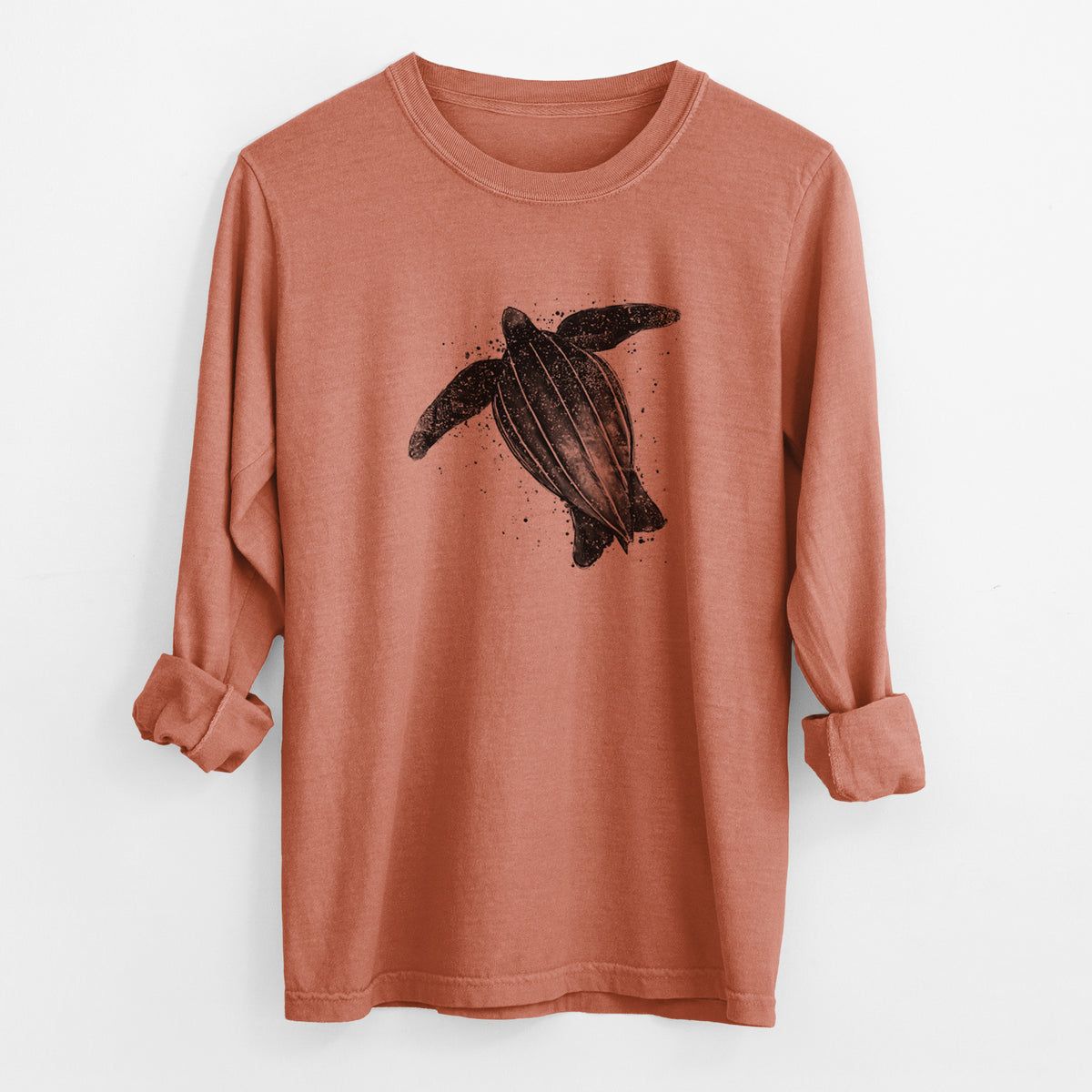 Yam burnt orange Comfort Colors long sleeve shirt laid flat with the cuffs rolled, printed with a black ink illustration of a leatherback sea turtle swimming, with ink splatters.