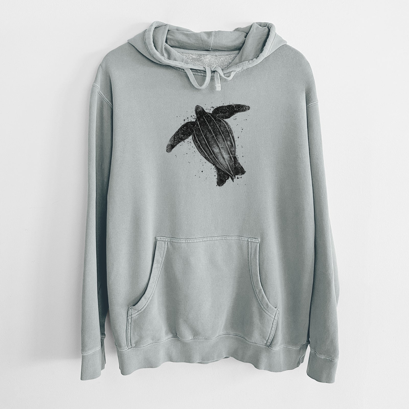 Sage green pigment dyed hoodie laid flat, printed with a black ink illustration of a leatherback sea turtle swimming, with ink splatters.