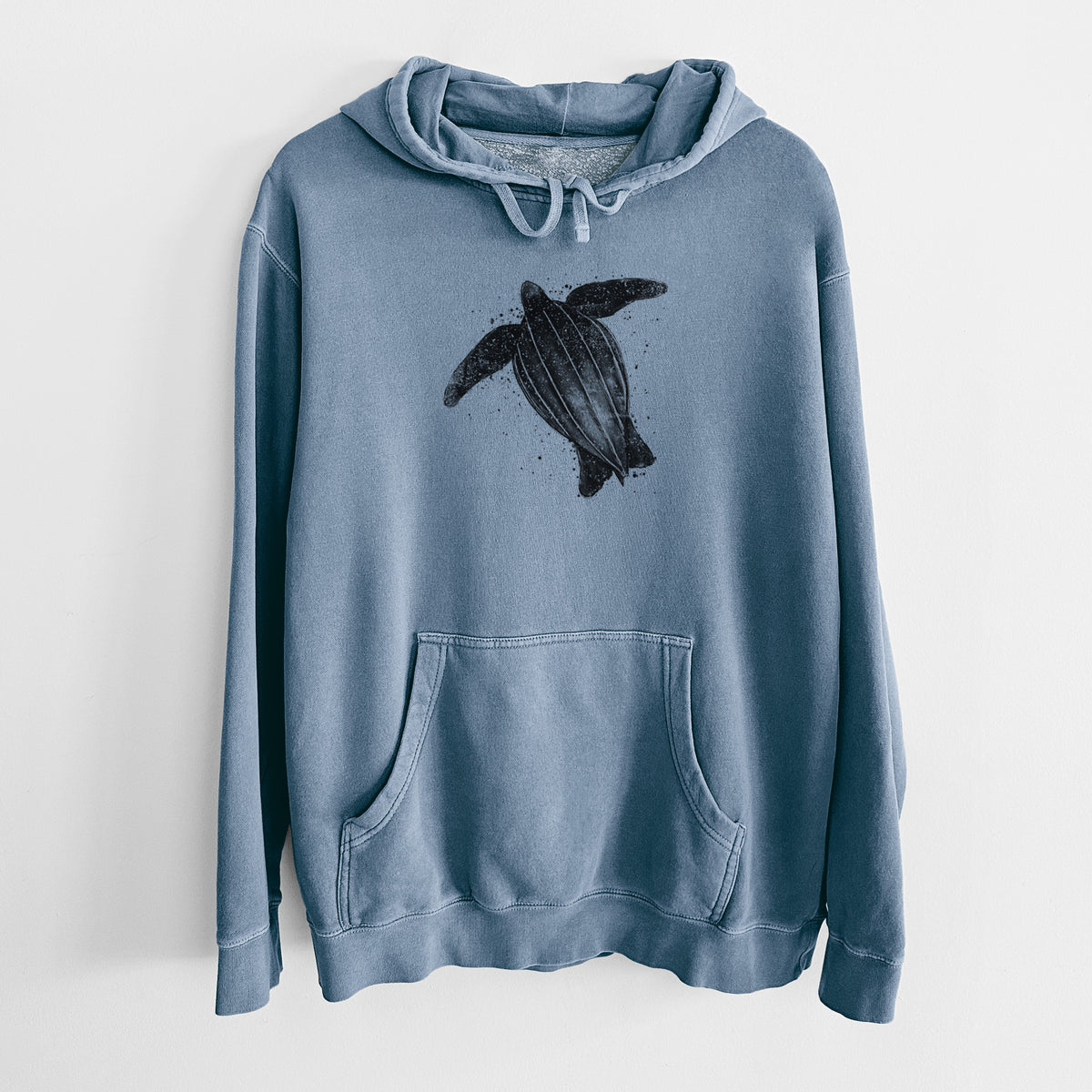 Slate blue pigment dyed hoodie laid flat, printed with a black ink illustration of a leatherback sea turtle swimming, with ink splatters.