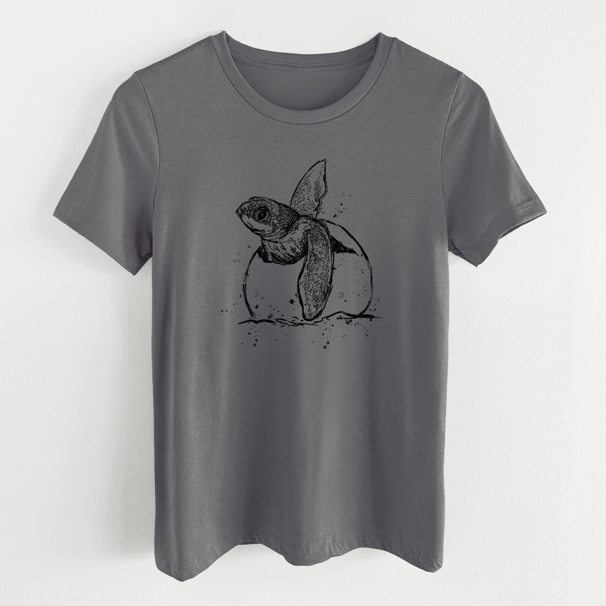 Asphalt women's relaxed fit cotton t-shirt laid flat, printed with a black ink illustration of a leatherback sea turtle hatchling emerging from its egg.
