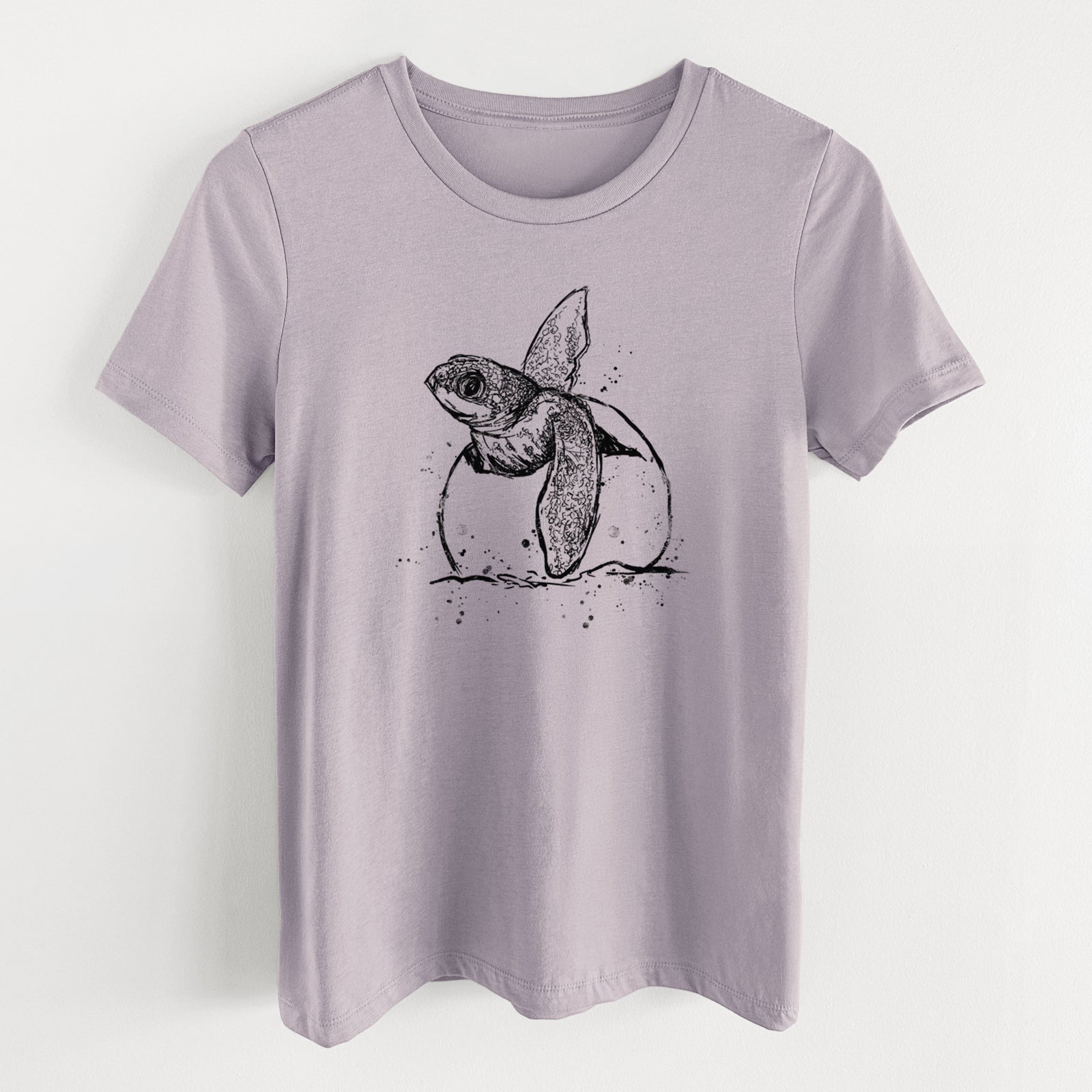 Light violet women's relaxed fit cotton t-shirt laid flat, printed with a black ink illustration of a leatherback sea turtle hatchling emerging from its egg.