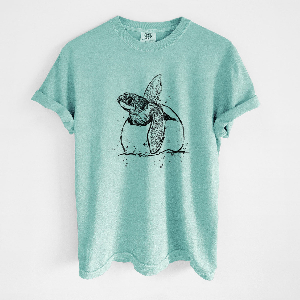 Chalky mint Comfort Colors t-shirt laid flat, printed with a black ink illustration of a leatherback sea turtle hatchling emerging from its egg.