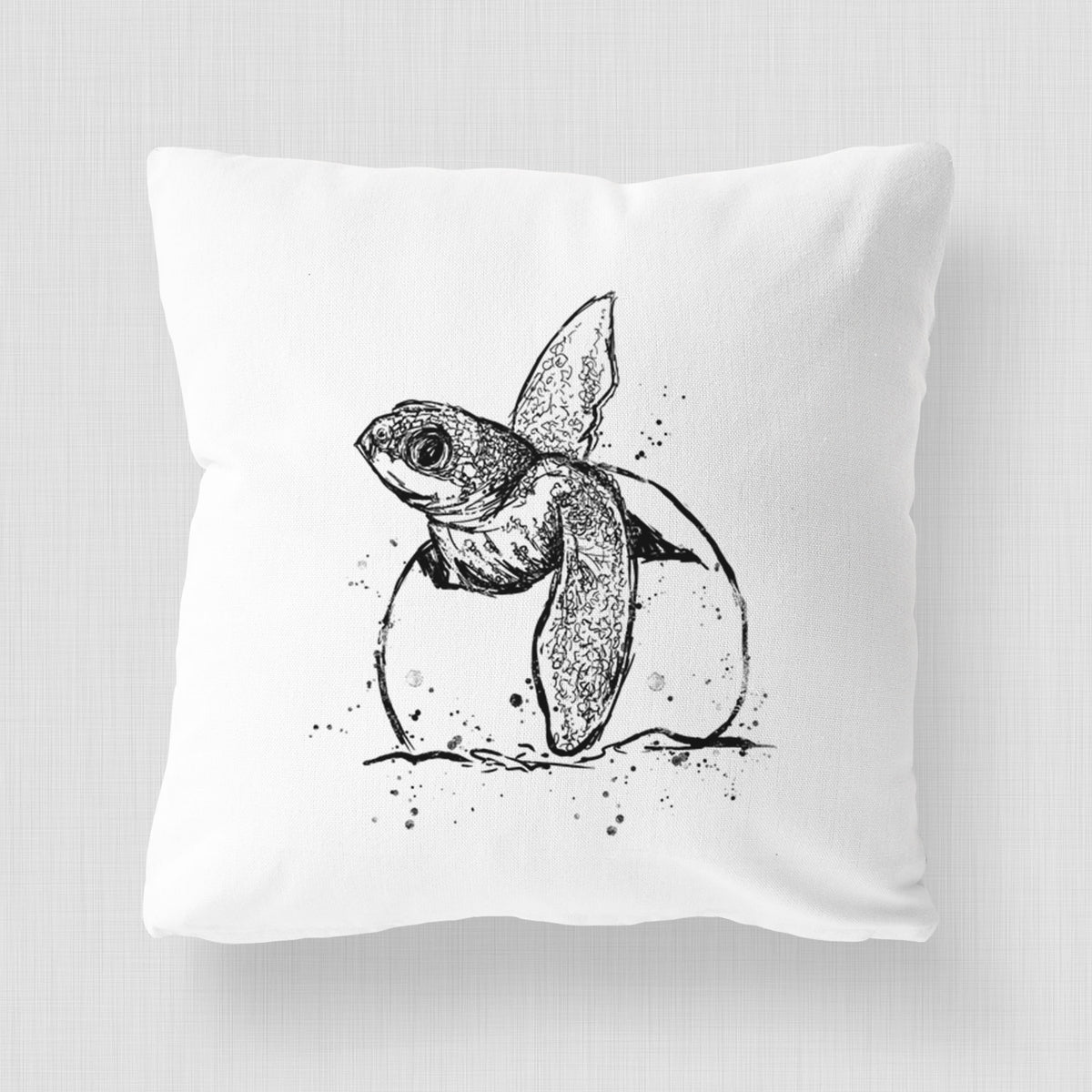 White pillow cover printed with a black ink illustration of a leatherback sea turtle hatchling emerging from its egg.