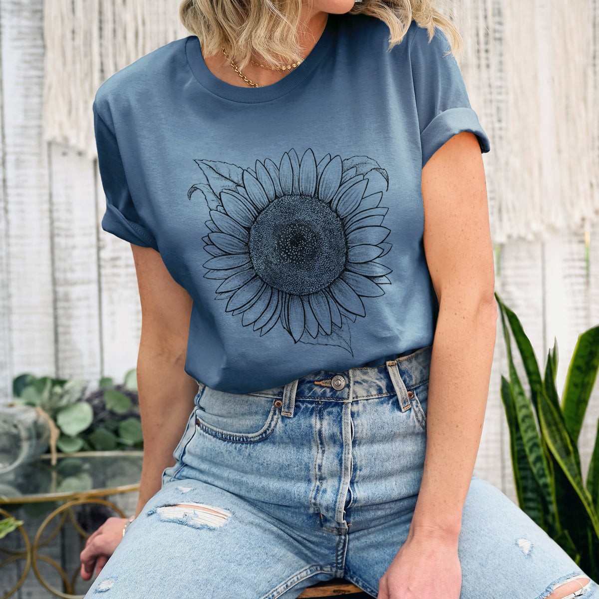 Woman wearing a steel blue lightweight cotton t-shirt printed with a detailed black ink line drawing of a Lemon Queen sunflower in bloom.