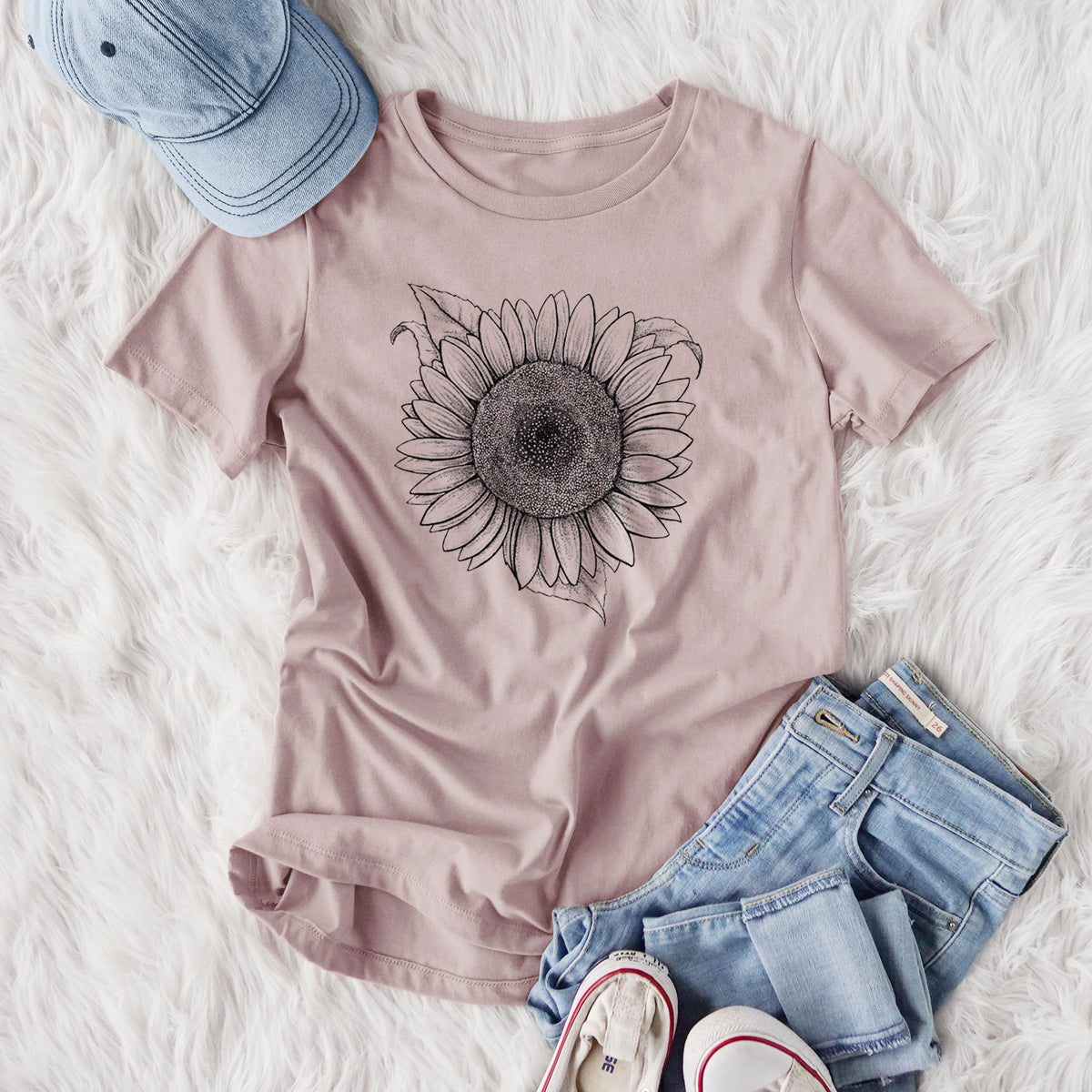 Women's relaxed fit cotton t-shirt printed with a detailed black ink line drawing of a Lemon Queen sunflower in bloom, styled flat on a white faux fur rug with jeans.