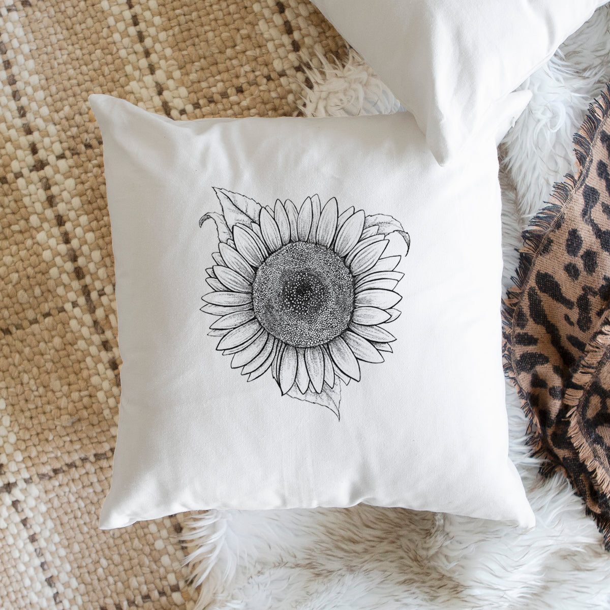 White pillow cover printed with a detailed black ink line drawing of a Lemon Queen sunflower in bloom, on a woven chair.