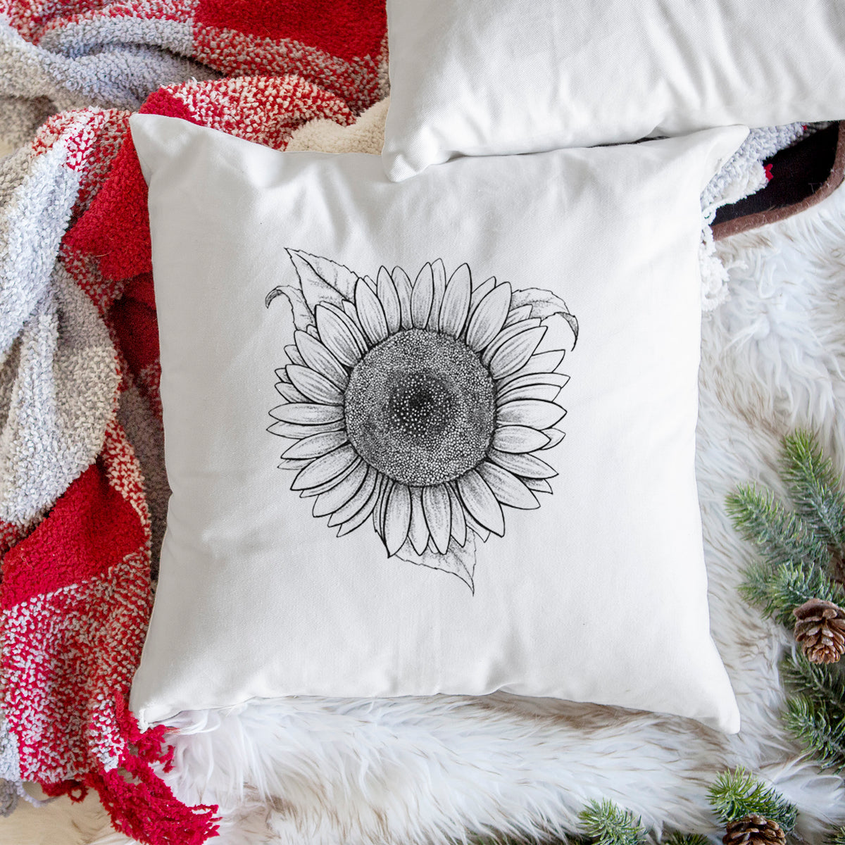 White pillow cover printed with a detailed black ink line drawing of a Lemon Queen sunflower in bloom, on a woven chair.
