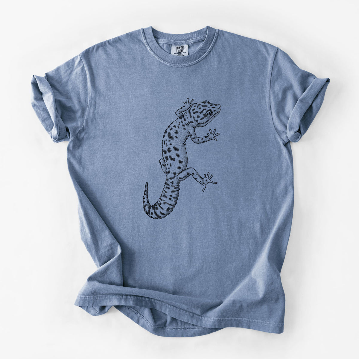 Blue jean Comfort Colors t-shirt laid flat, printed with a detailed black ink illustration of a spotted leopard gecko climbing.