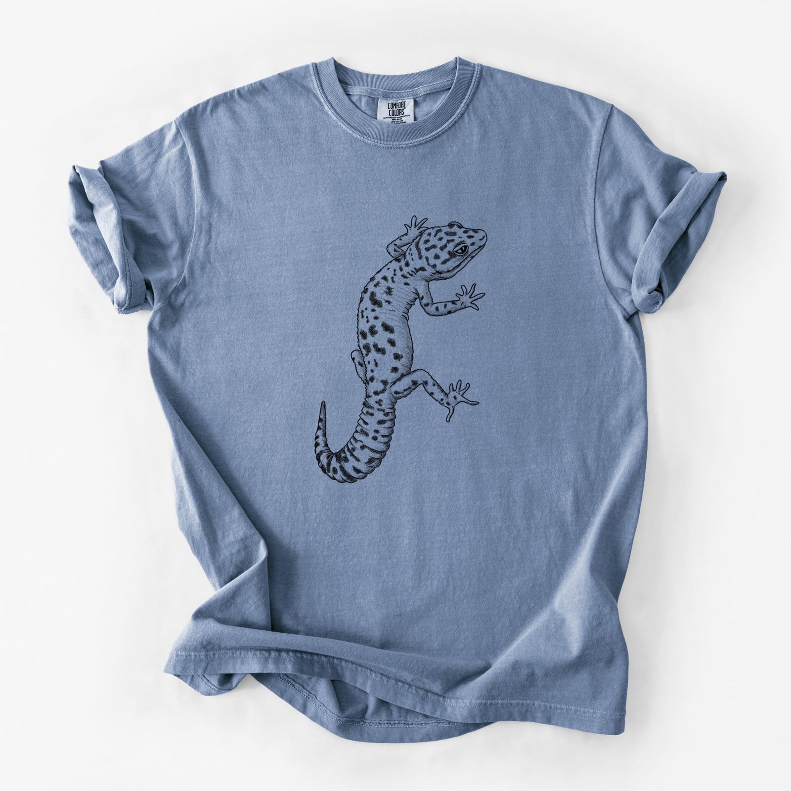 Blue jean Comfort Colors t-shirt laid flat, printed with a detailed black ink illustration of a spotted leopard gecko climbing.