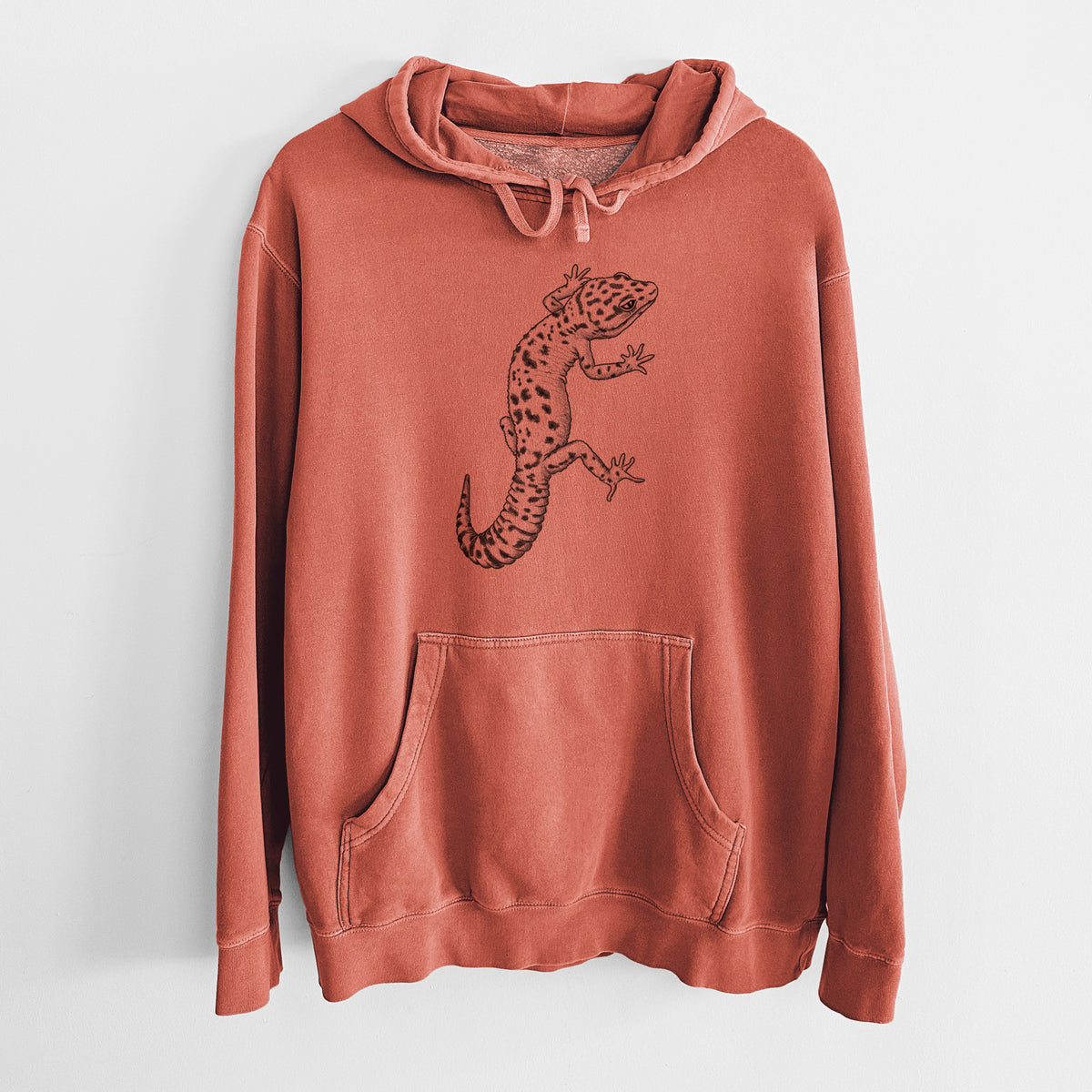 Amber orange pigment dyed hoodie laid flat, printed with a detailed black ink illustration of a spotted leopard gecko climbing.
