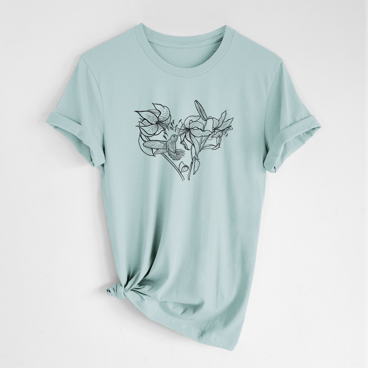 Dusty blue lightweight cotton t-shirt laid flat with the sleeves rolled, printed with a black ink line drawing of lilies and a hummingbird arranged in a heart shape.