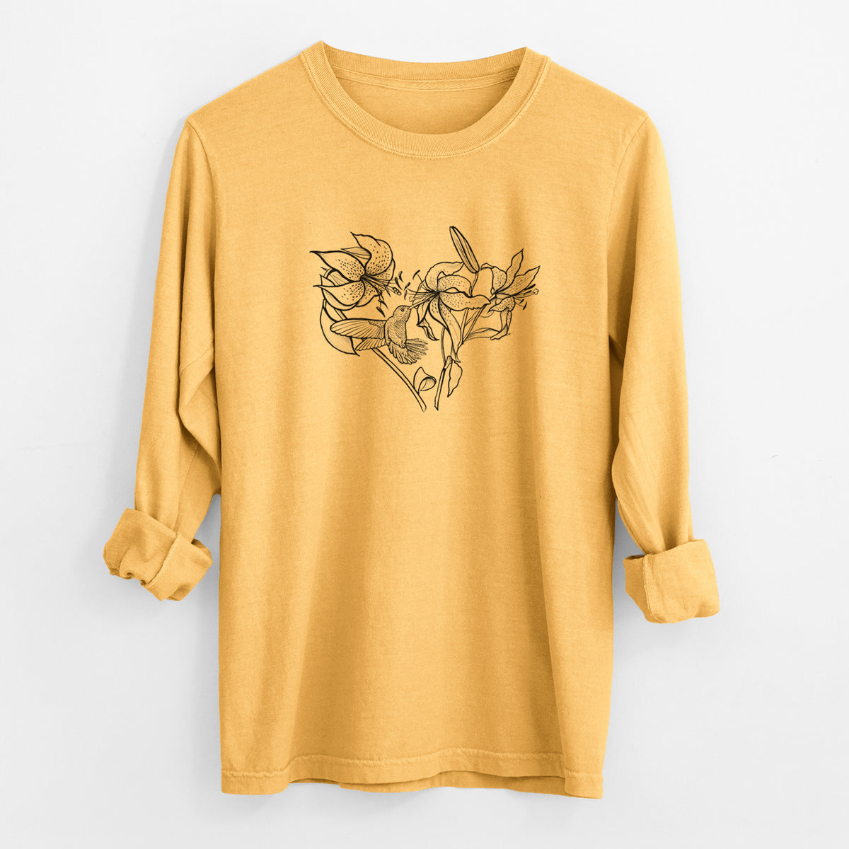Golden wheat yellow Comfort Colors long sleeve shirt laid flat with the cuffs rolled, printed with a black ink line drawing of lilies and a hummingbird arranged in a heart shape.
