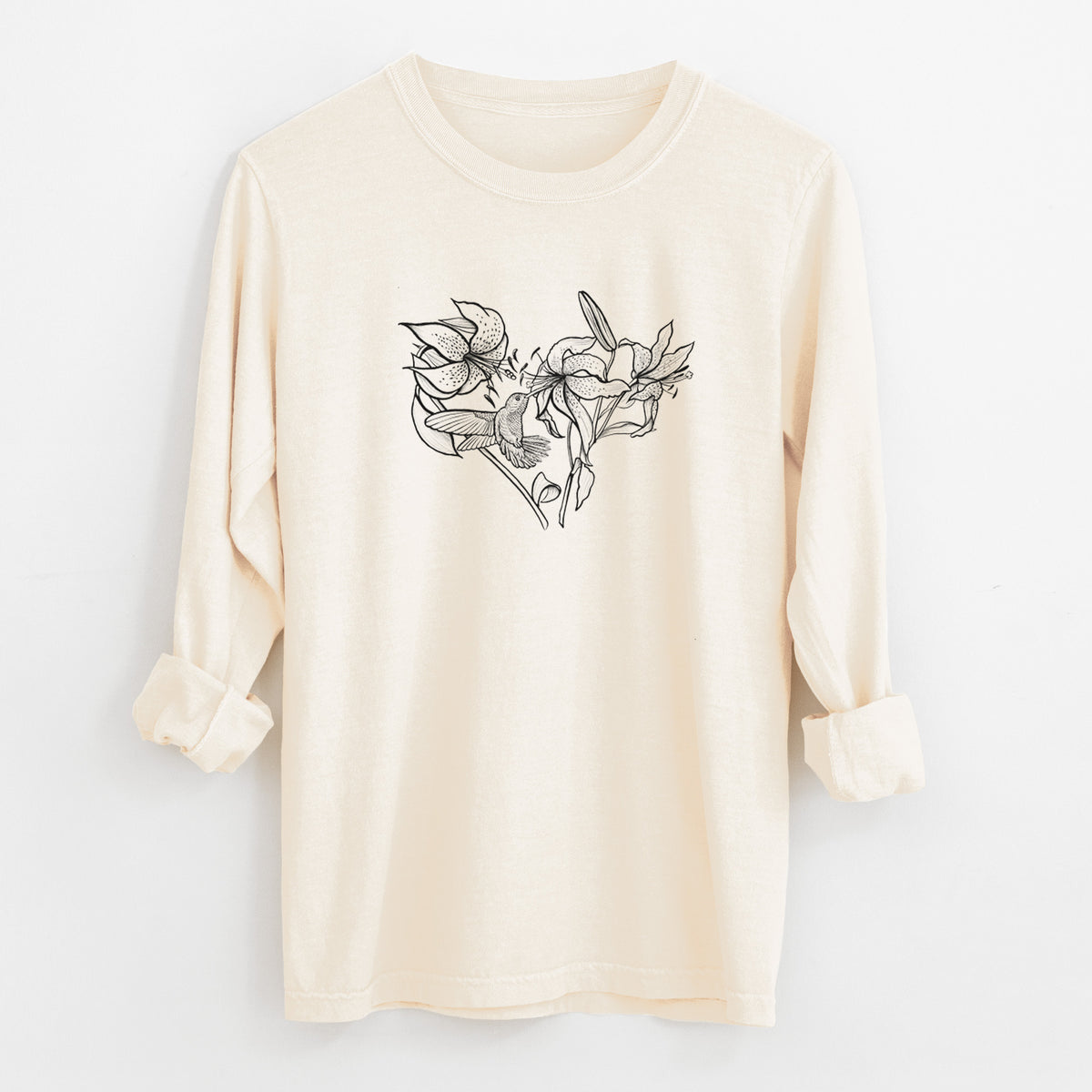 Ivory Comfort Colors long sleeve shirt laid flat with the cuffs rolled, printed with a black ink line drawing of lilies and a hummingbird arranged in a heart shape.